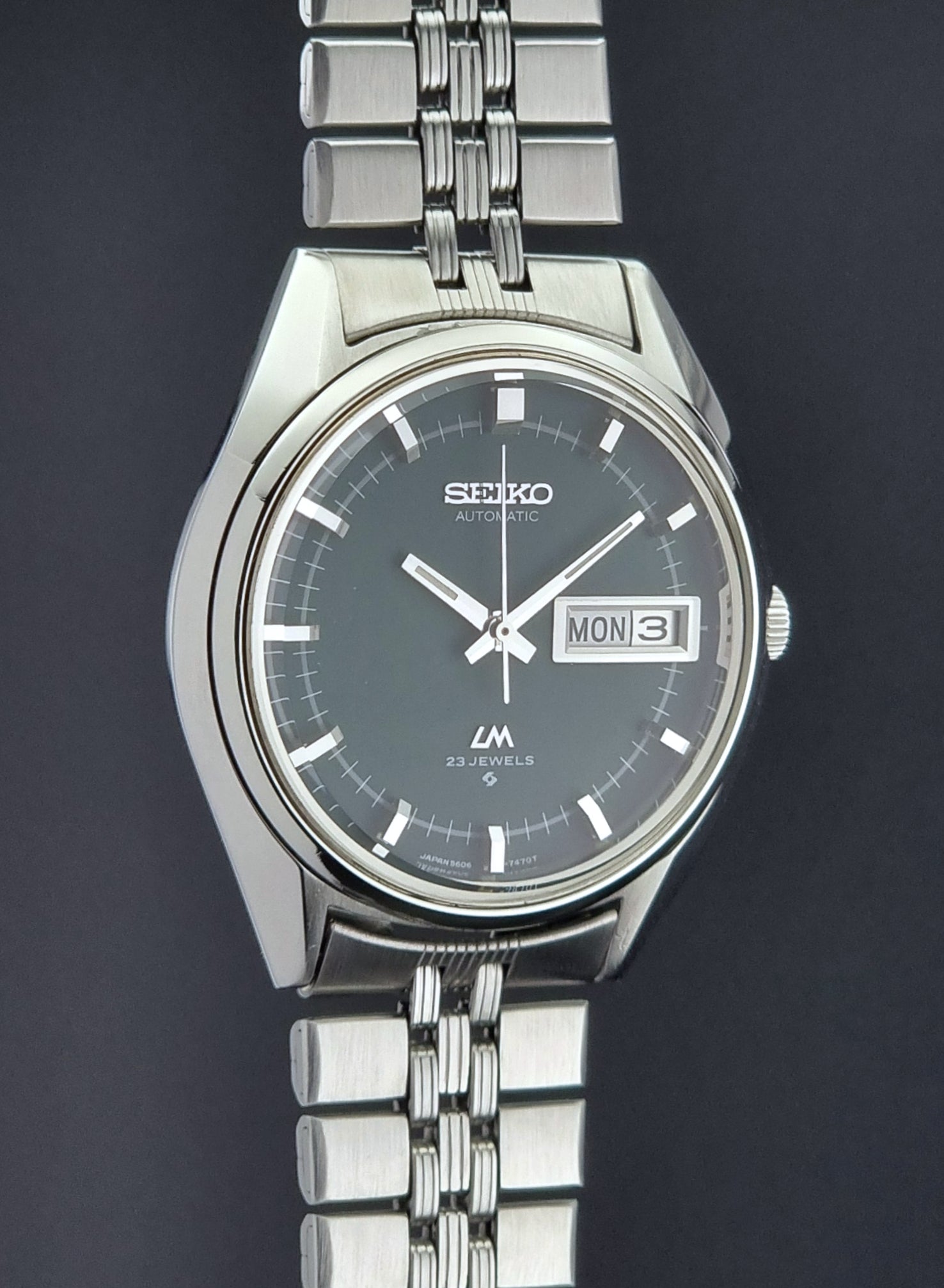 Silver Seiko watch with a dark face on a black background