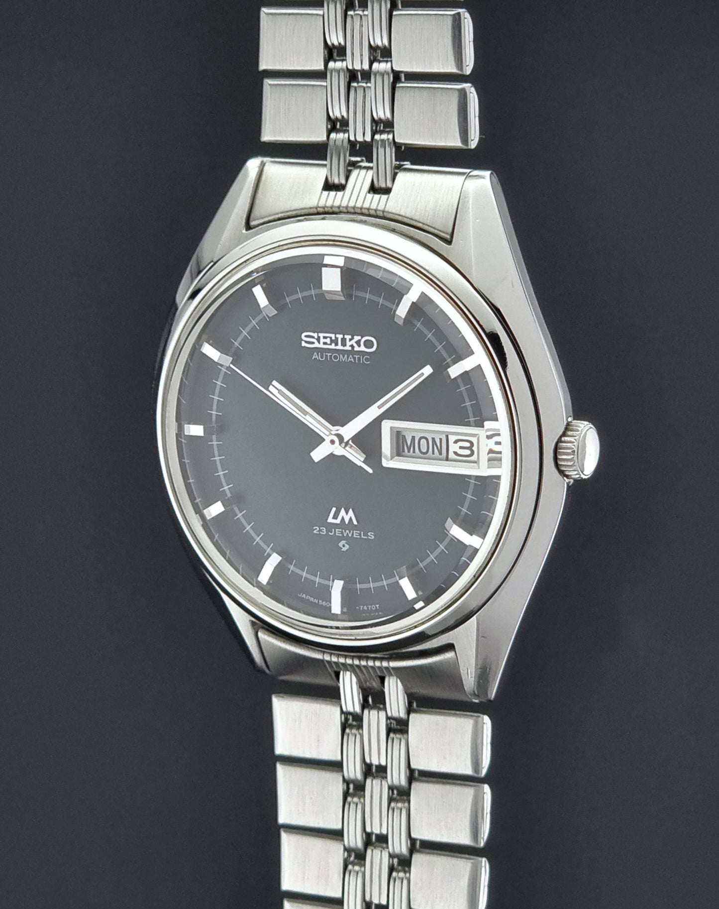 Silver Seiko watch with a dark face on a black background