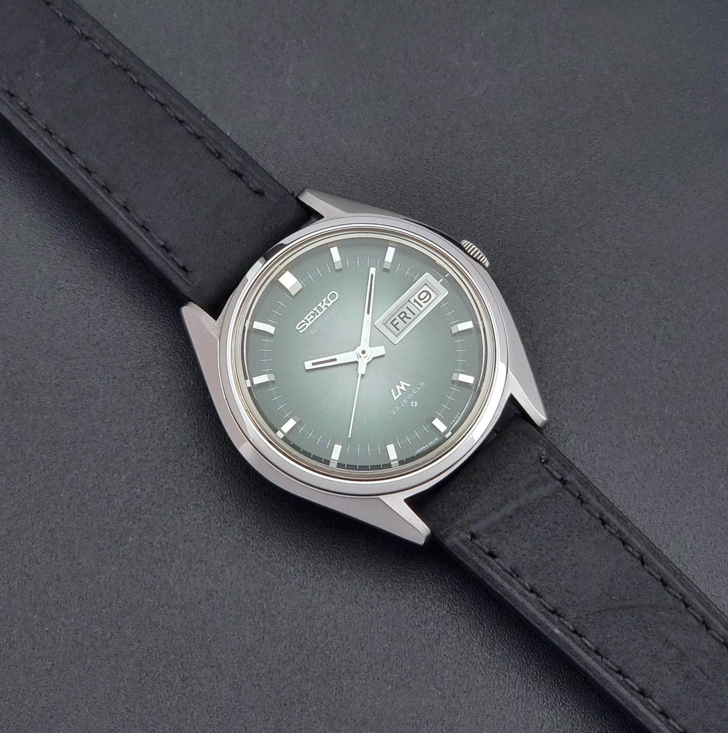Vintage Seiko LordMatic 5606-7191 watch with a black leather strap on a dark gray background dial