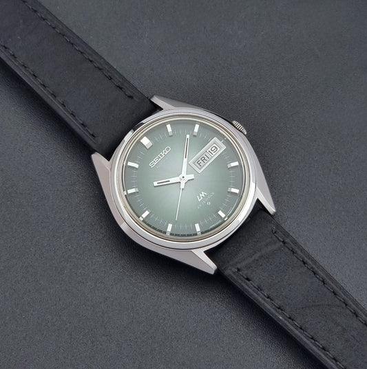Vintage Seiko LordMatic 5606-7191 watch with a black leather strap on a dark gray background dial