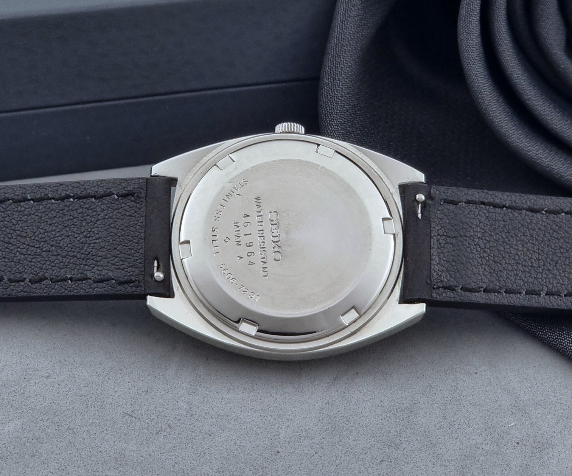 Vintage Seiko Wristwatch 5606-7231 LordMatic black strap and blue dial on a gray background case back view