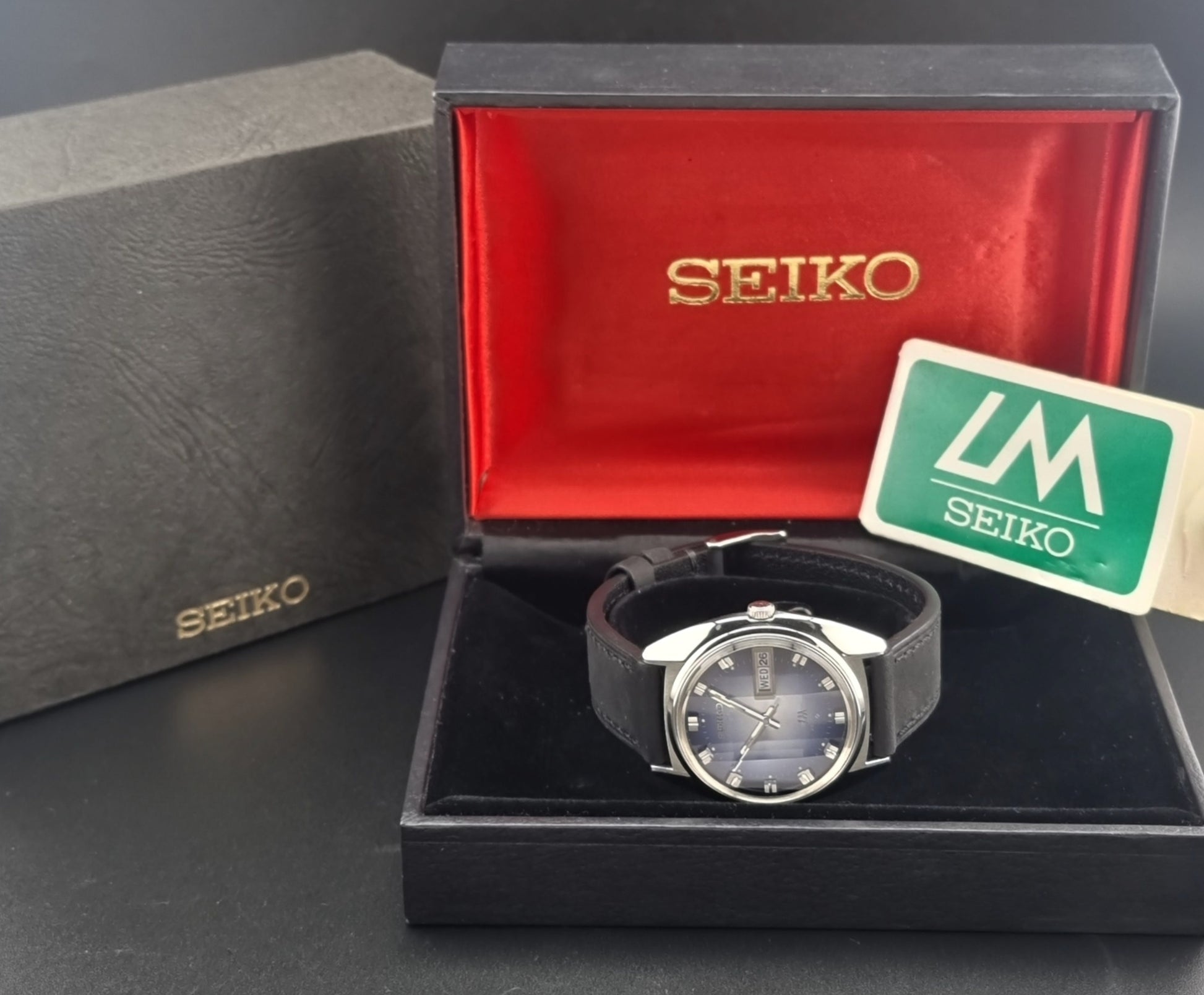 Vintage Seiko Wristwatch 5606-7231 LordMatic black strap and blue dial on a gray background box view