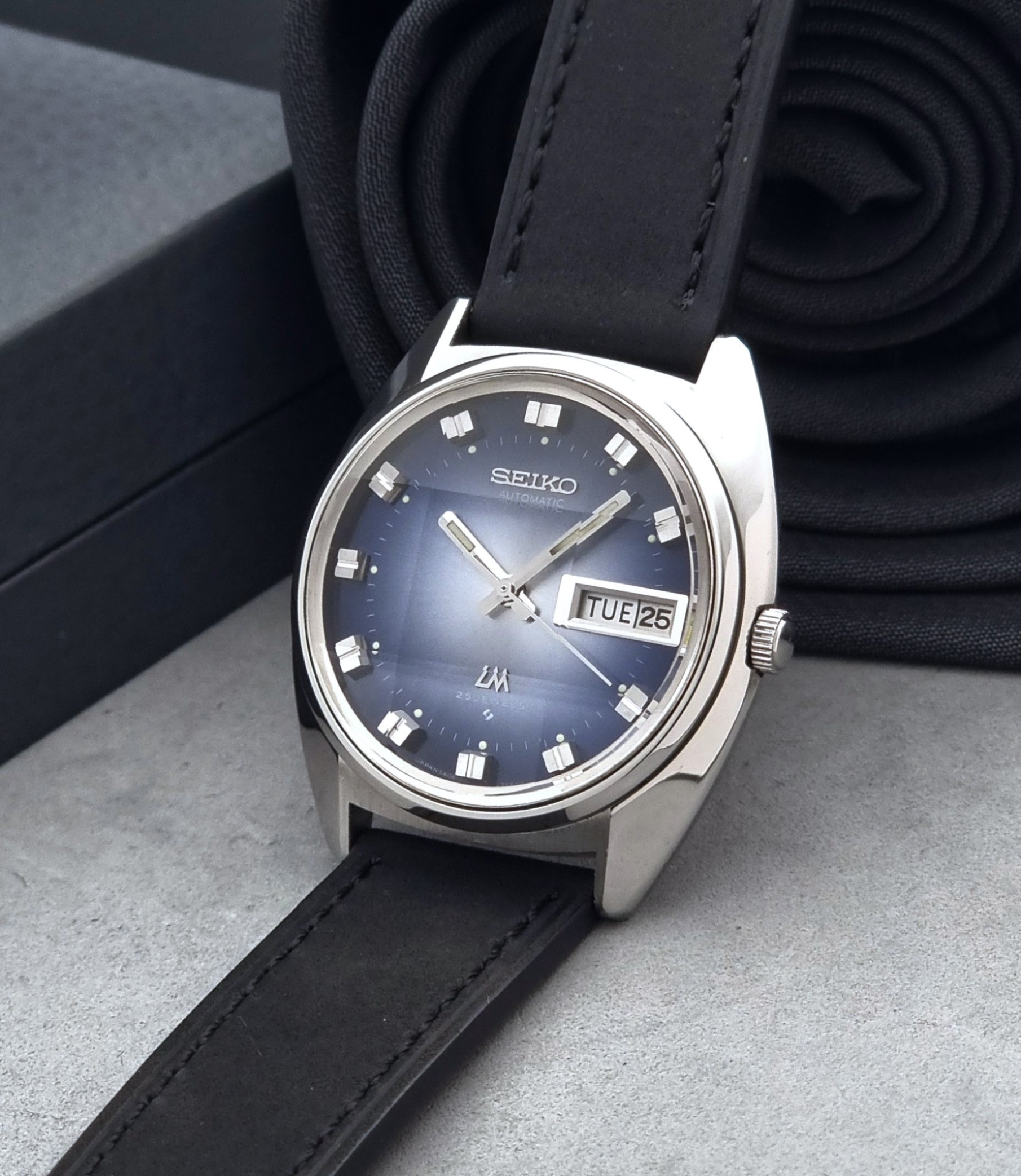 Vintage Seiko Wristwatch 5606-7231 LordMatic black strap and blue dial on a gray background crown view
