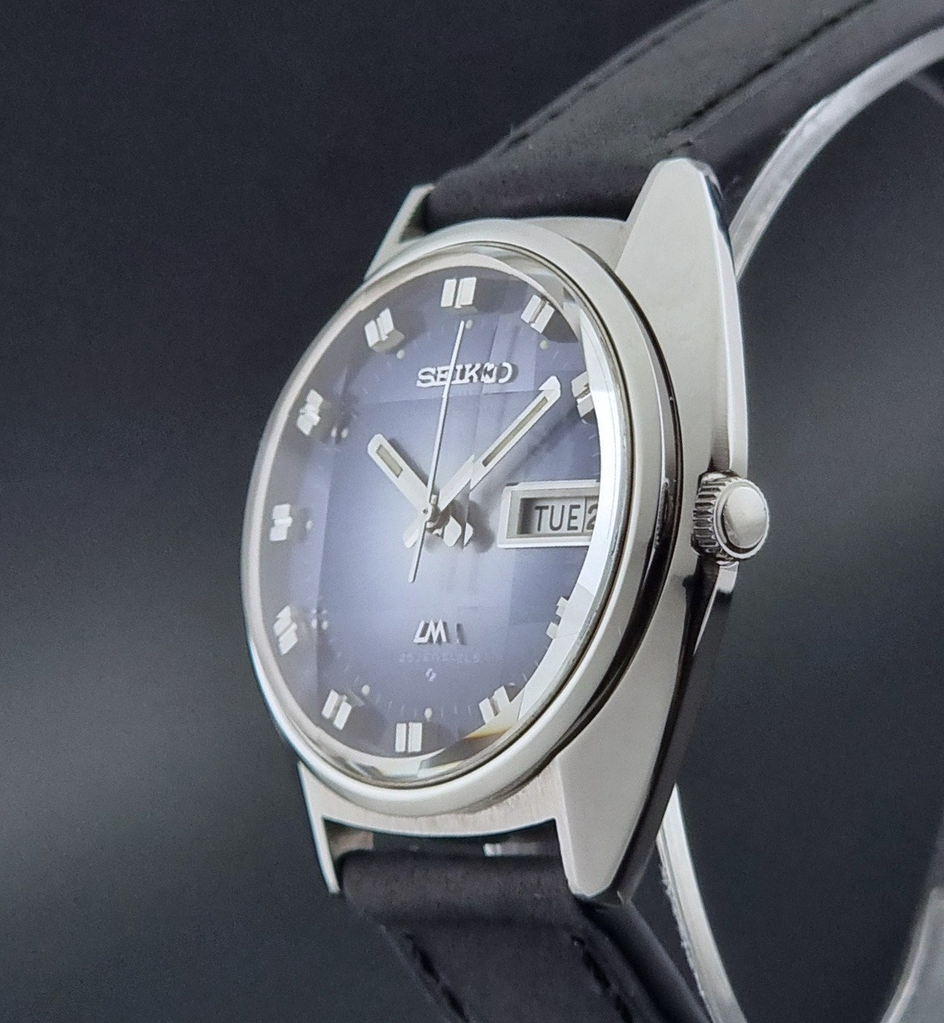 Vintage Seiko Wristwatch 5606-7231 LordMatic black strap and blue dial on a gray background crown profile view
