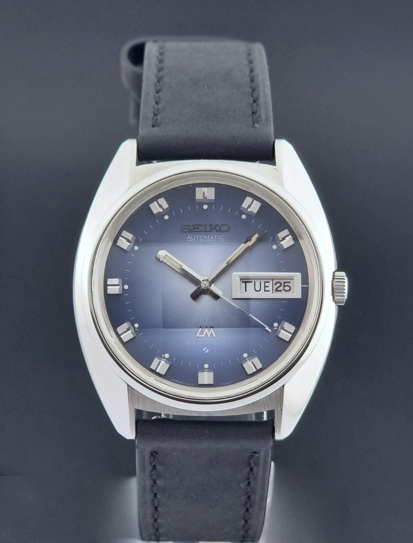 Vintage Seiko Wristwatch 5606-7231 LordMatic black strap and blue dial on a gray background close dial view