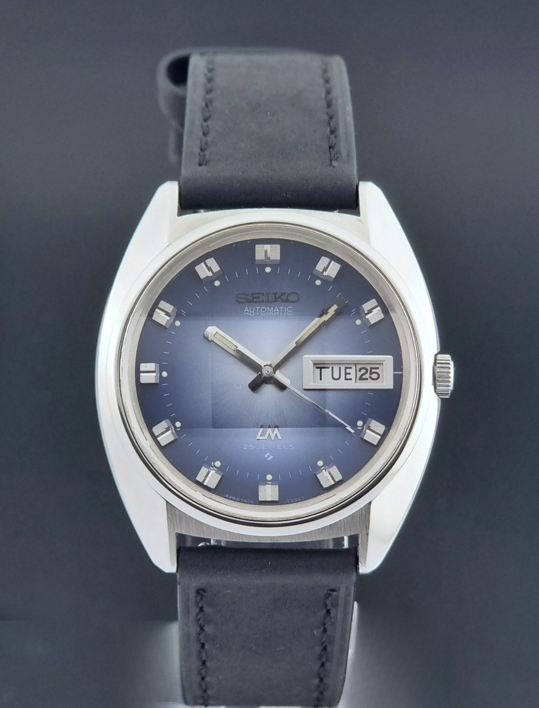 Vintage Seiko Wristwatch 5606-7231 LordMatic black strap and blue dial on a gray background close dial view