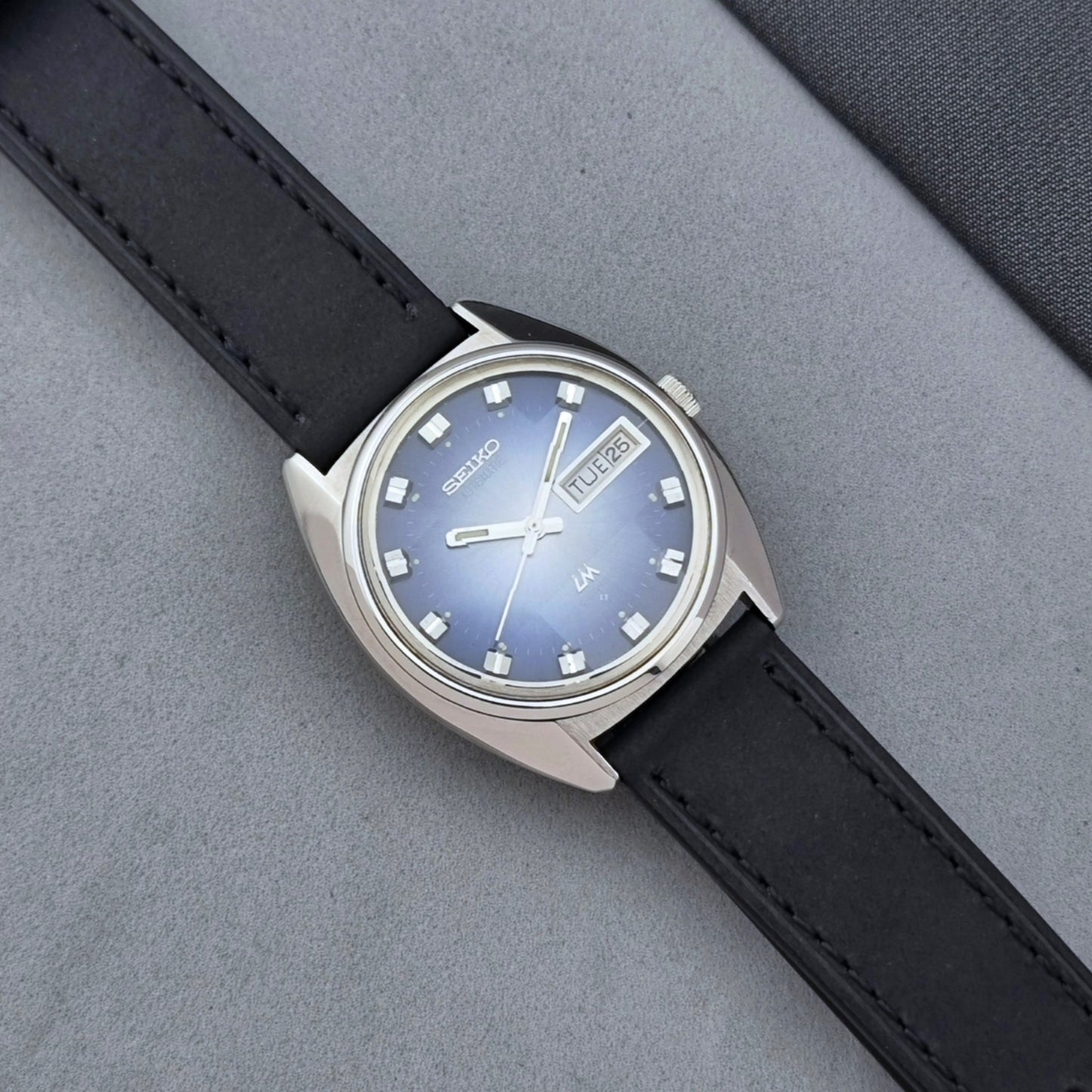 Vintage Seiko Wristwatch 5606-7231 LordMatic black strap and blue dial on a gray background dial