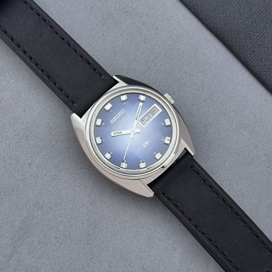 Vintage Seiko Wristwatch 5606-7231 LordMatic black strap and blue dial on a gray background dial