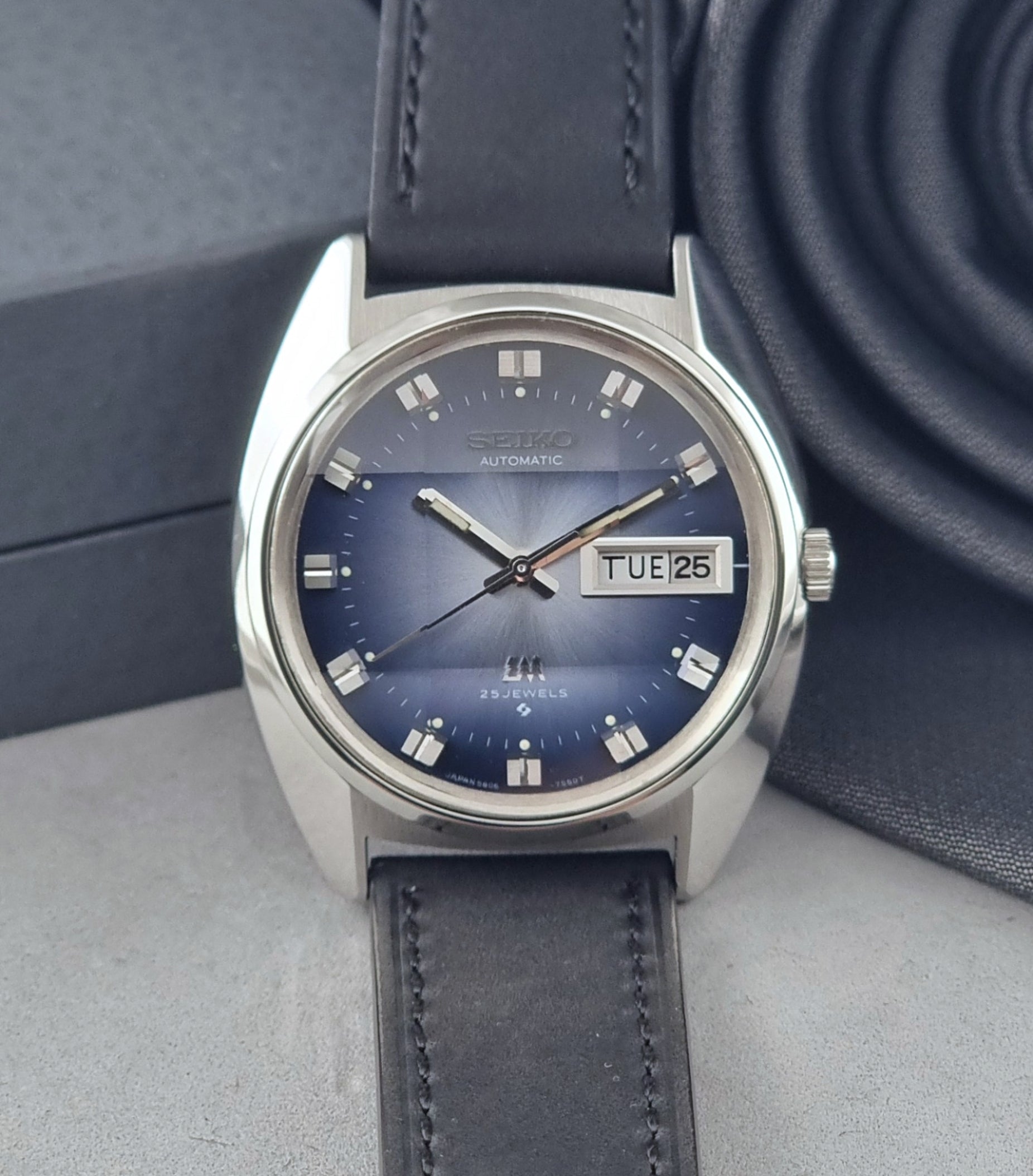 Vintage Seiko Wristwatch 5606-7231 LordMatic black strap and blue dial on a gray background dial view