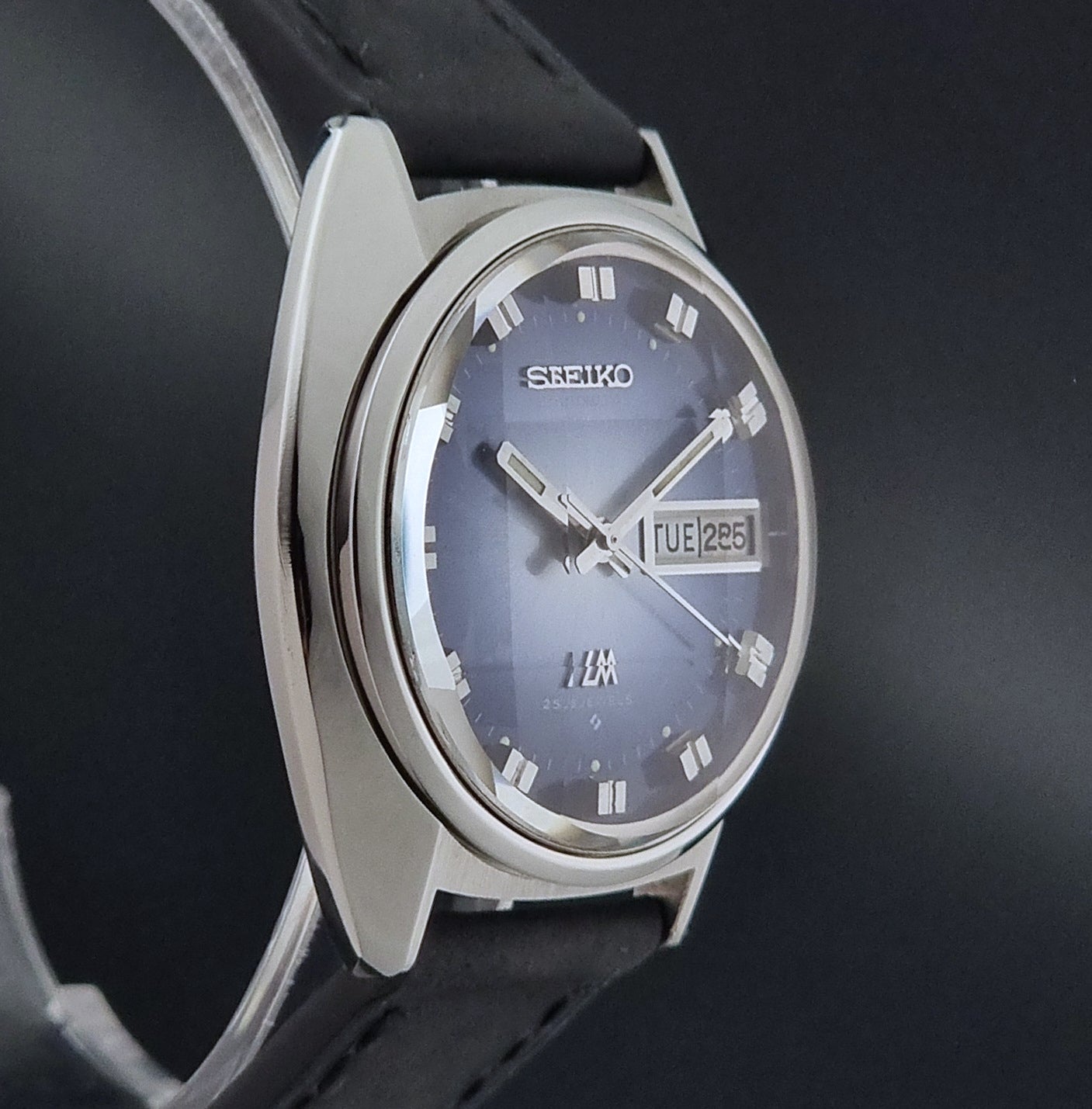 Vintage Seiko Wristwatch 5606-7231 LordMatic black strap and blue dial on a gray background side profile view