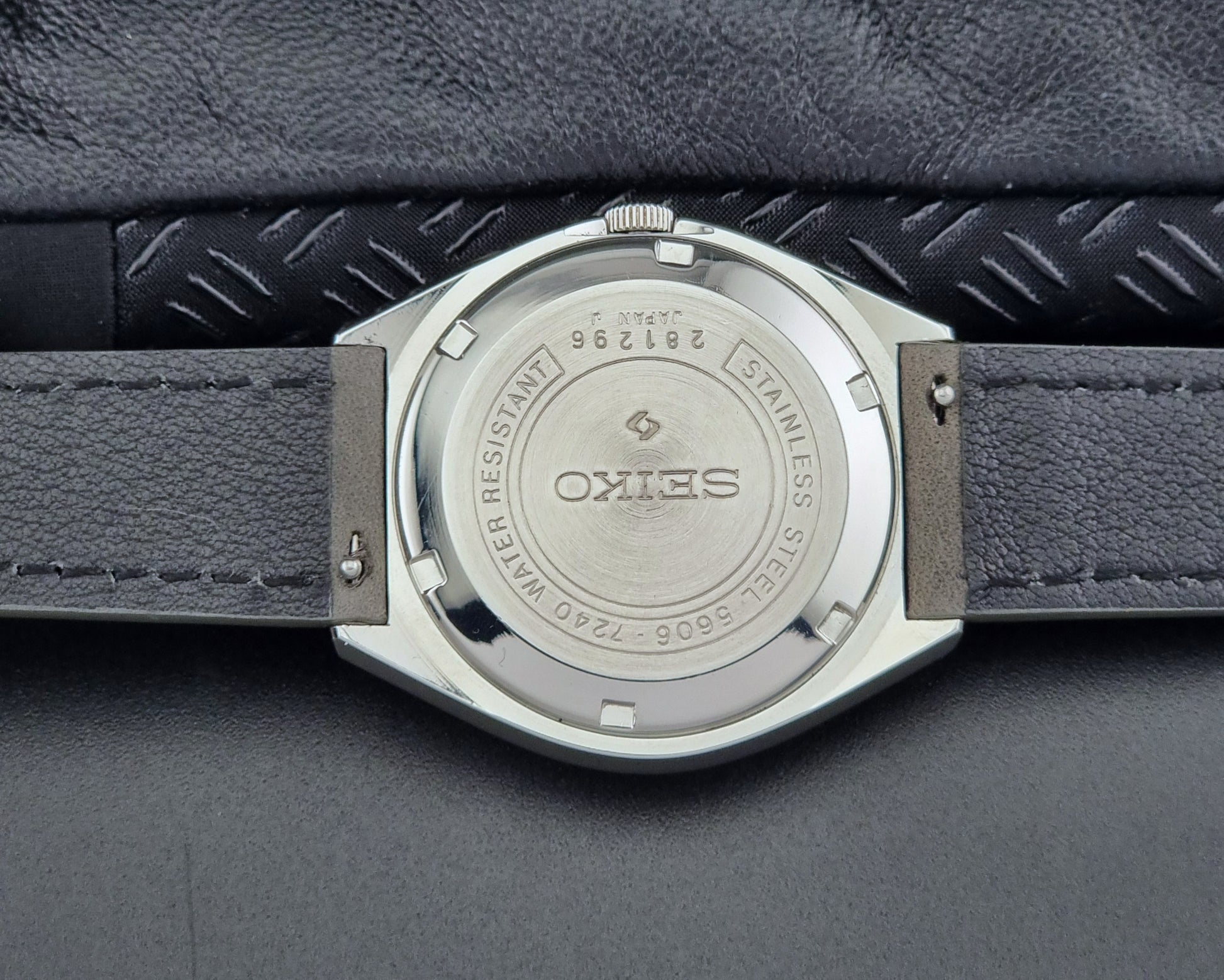 Close-up of a Seiko watch back with 'Stainless Steel' text on a textured gray background