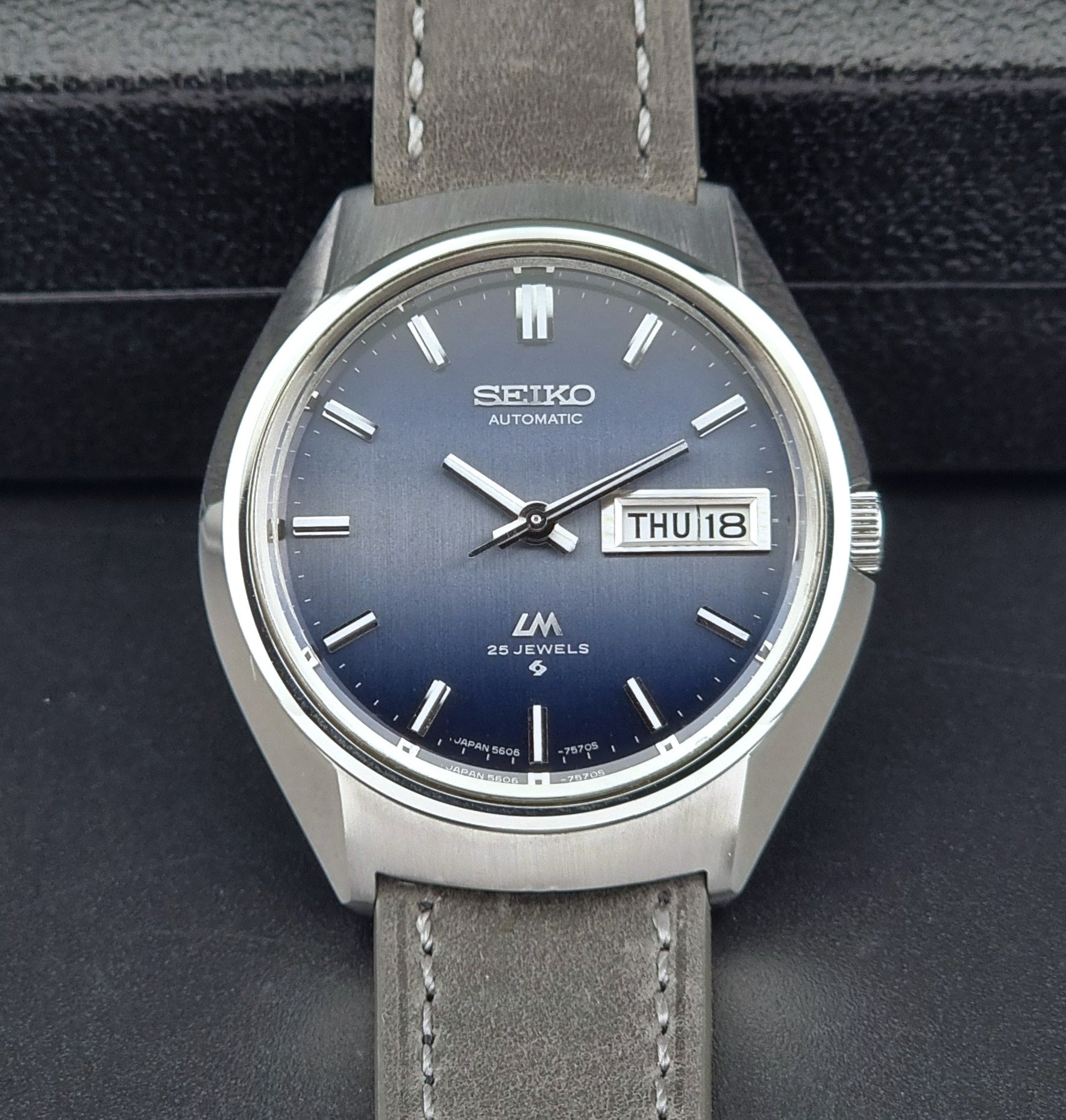 Vintage Seiko 5606-7240 watch with blue dial and gray leather strap on a dark background
