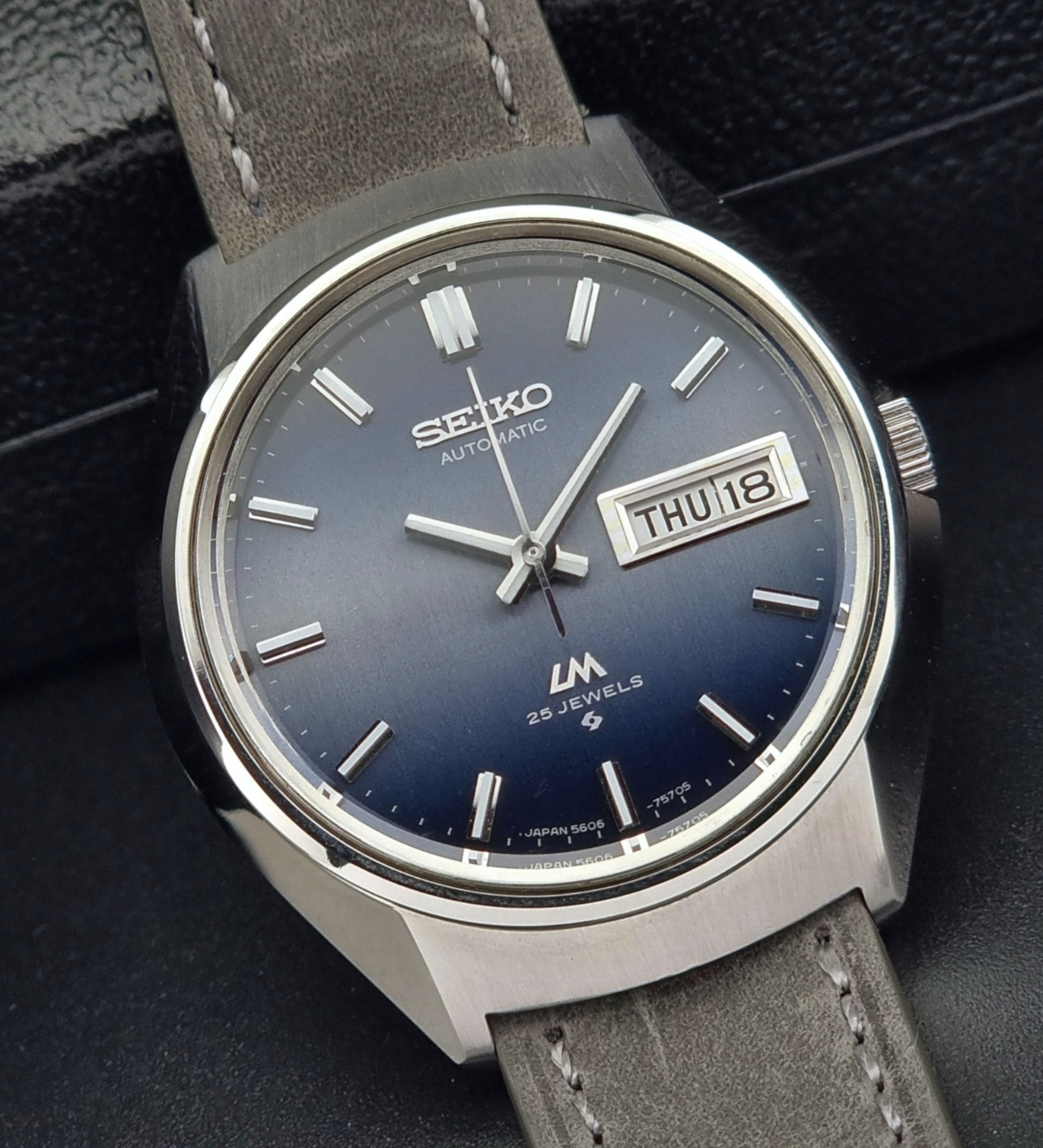 Vintage Seiko 5606-7240 watch with blue dial and gray leather strap on a dark background