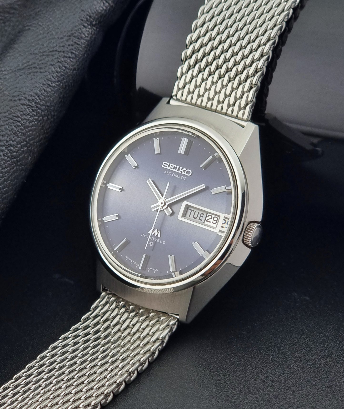 Silver Seiko watch with mesh band on a dark background