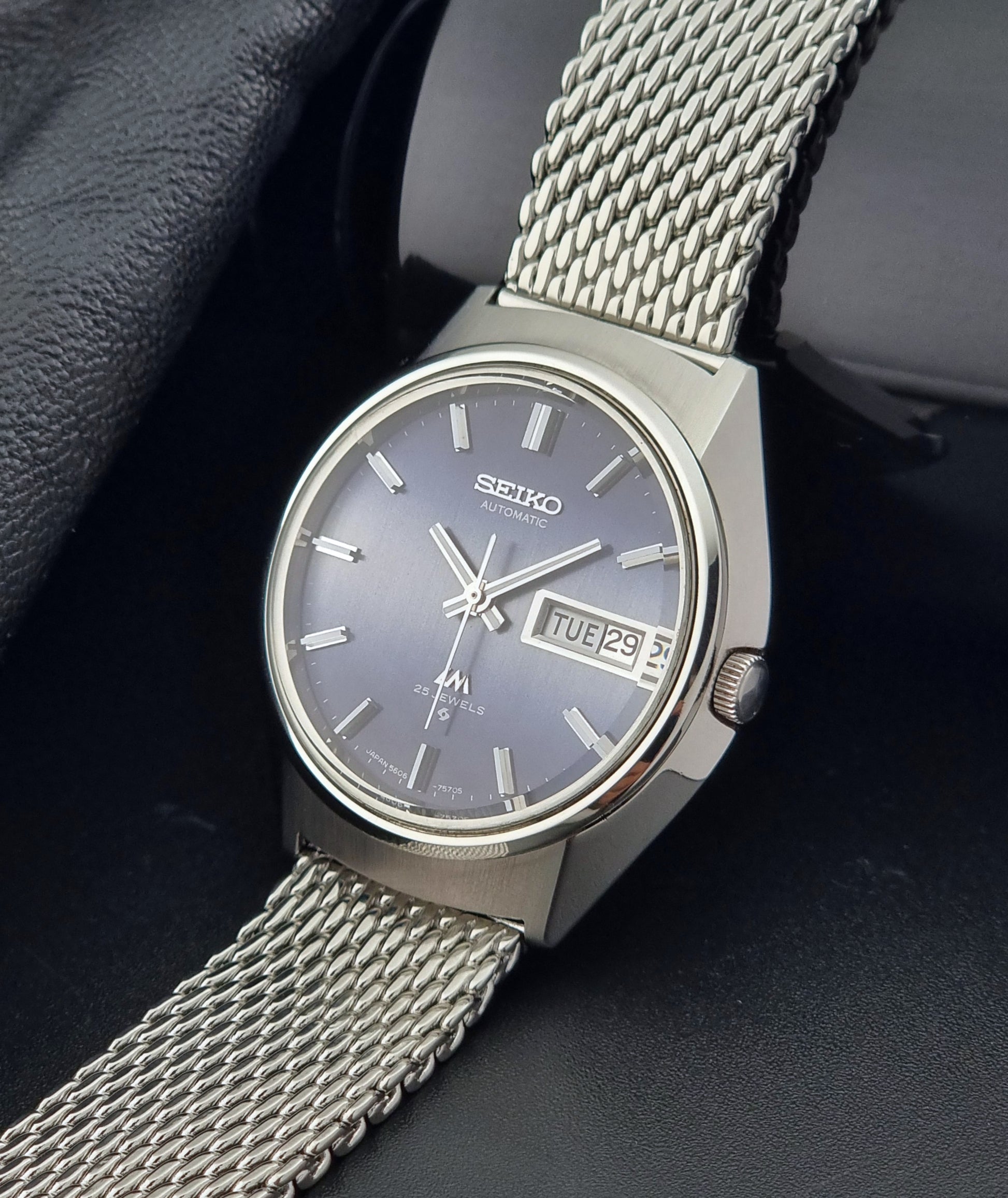 Silver Seiko watch with mesh band on a dark background