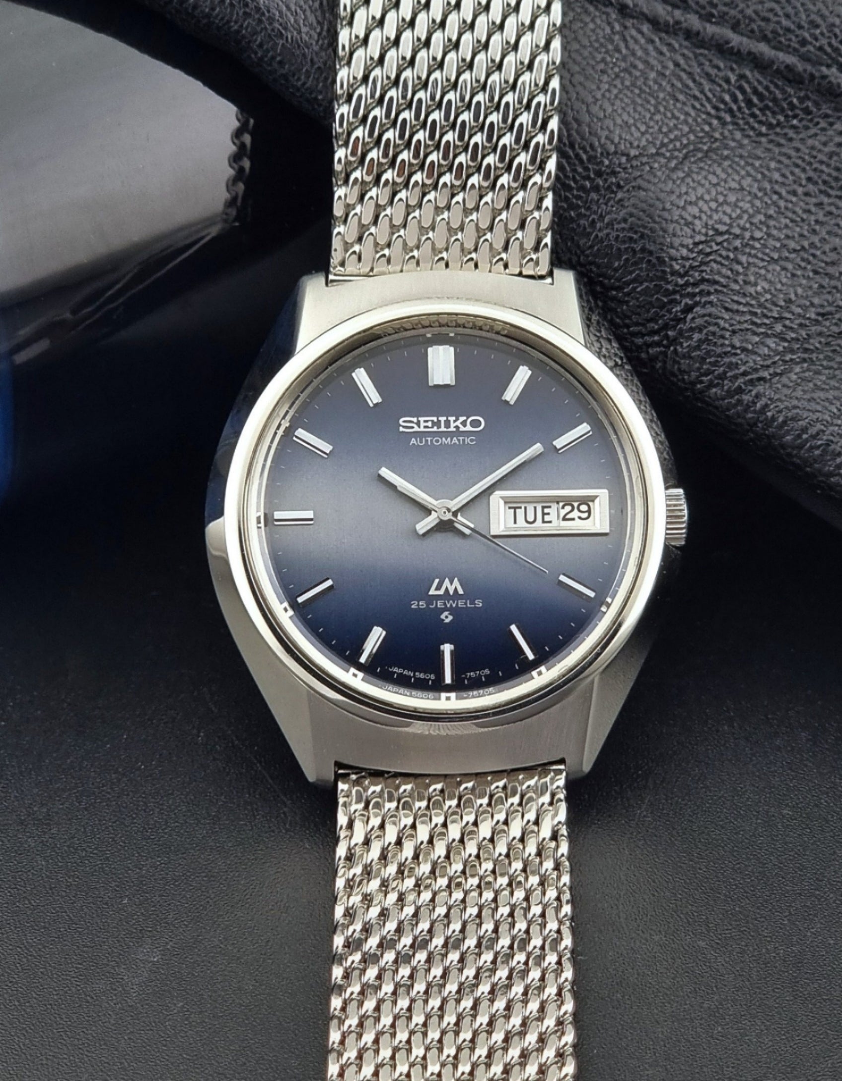 Seiko watch with silver mesh strap on a dark background