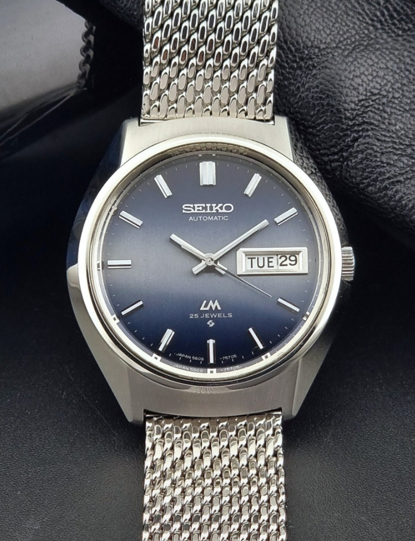 Seiko watch with blue gradient dial and mesh band on a dark background
