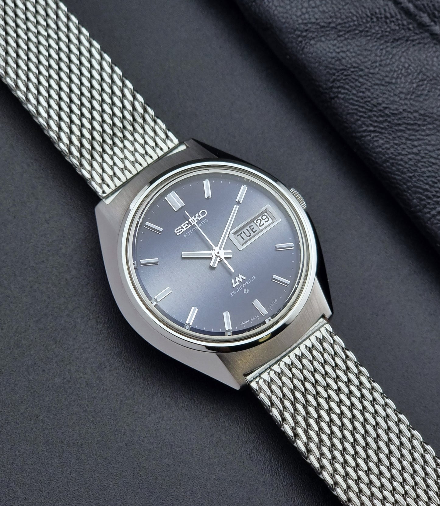 Silver Seiko watch with mesh band on a dark background