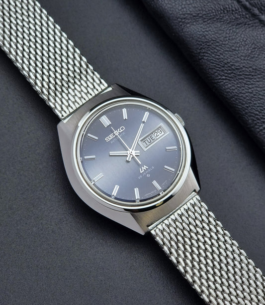 Silver Seiko watch with mesh band on a dark background