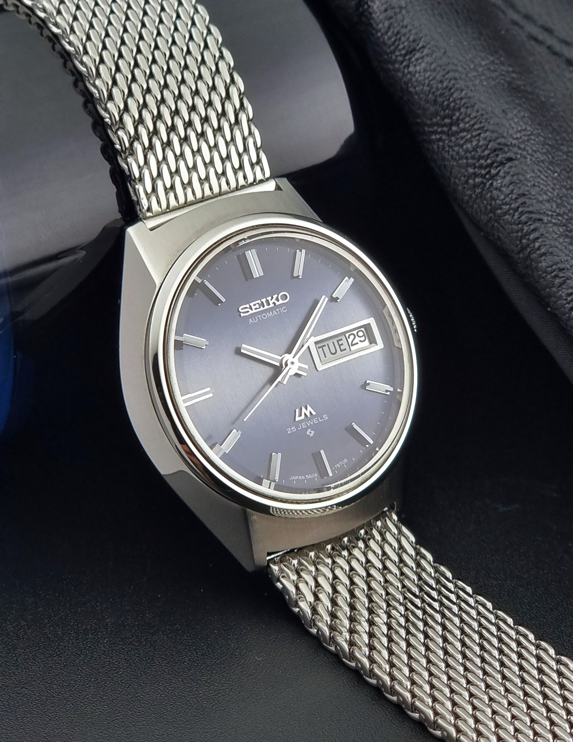 Silver Seiko watch with mesh band on a dark background