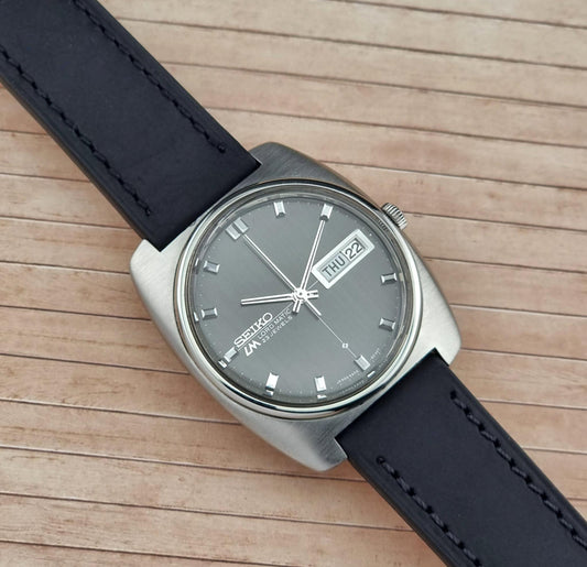 Seiko Lord Matic watch with black leather strap on a wooden surface