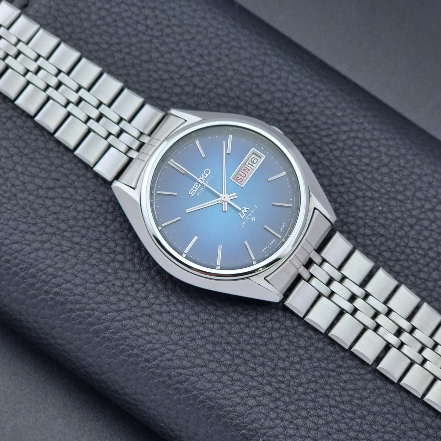 Vintage Seiko Wristwatch LordMatic 5606-8030 with blue gradient dial on a dark textured surface front