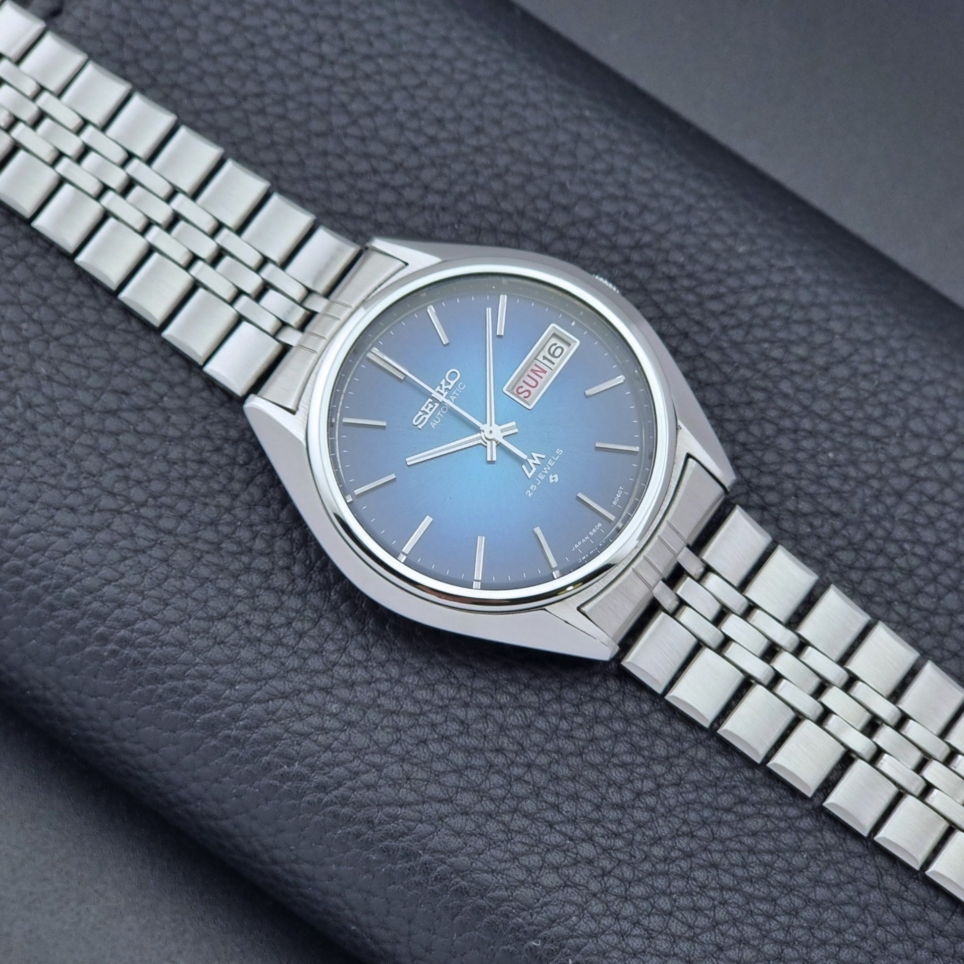 Vintage Seiko Wristwatch LordMatic 5606-8030 with blue gradient dial on a dark textured surface front