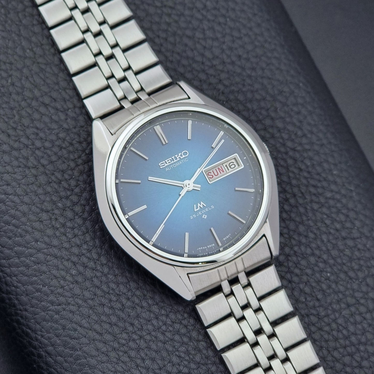 Vintage Seiko Wristwatch LordMatic 5606-8030 with blue gradient dial on a dark textured surface close dial view