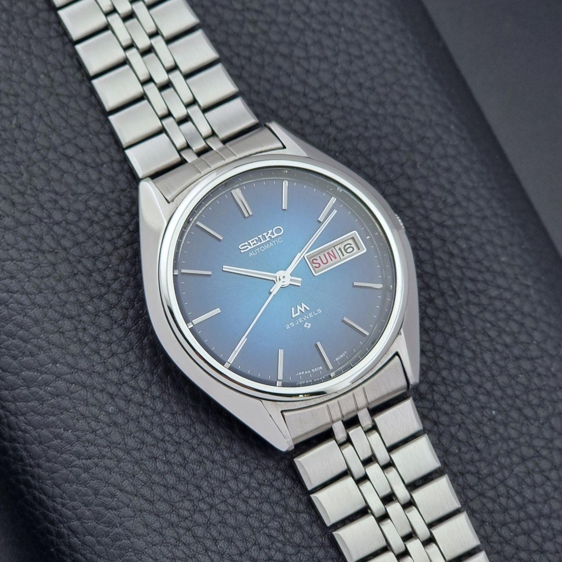 Vintage Seiko Wristwatch LordMatic 5606-8030 with blue gradient dial on a dark textured surface close dial view