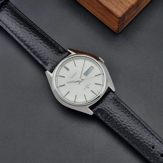 Vintage Seiko watch LordMatic 5606-8031 with black leather strap and silver case on a dark surface front