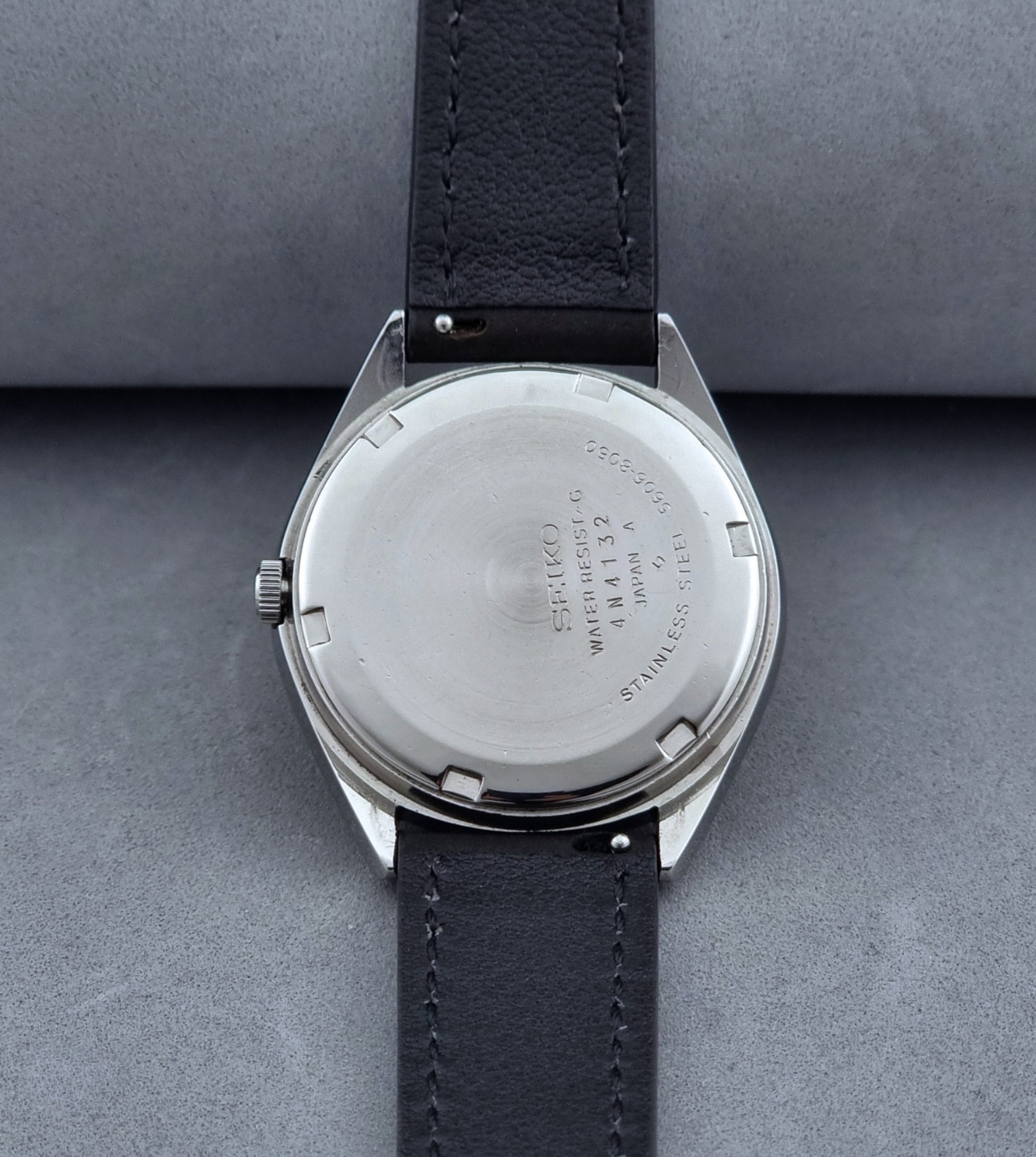 Vintage Seiko Wristwatch LordMatic 5606-8050 with blue gradient dial on a dark surface case back view