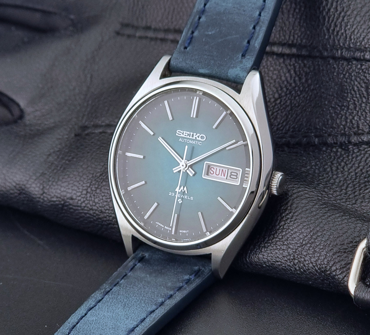 Vintage Seiko watch LordMatic 5606-8050 with blue leather strap on a dark gray background crown view