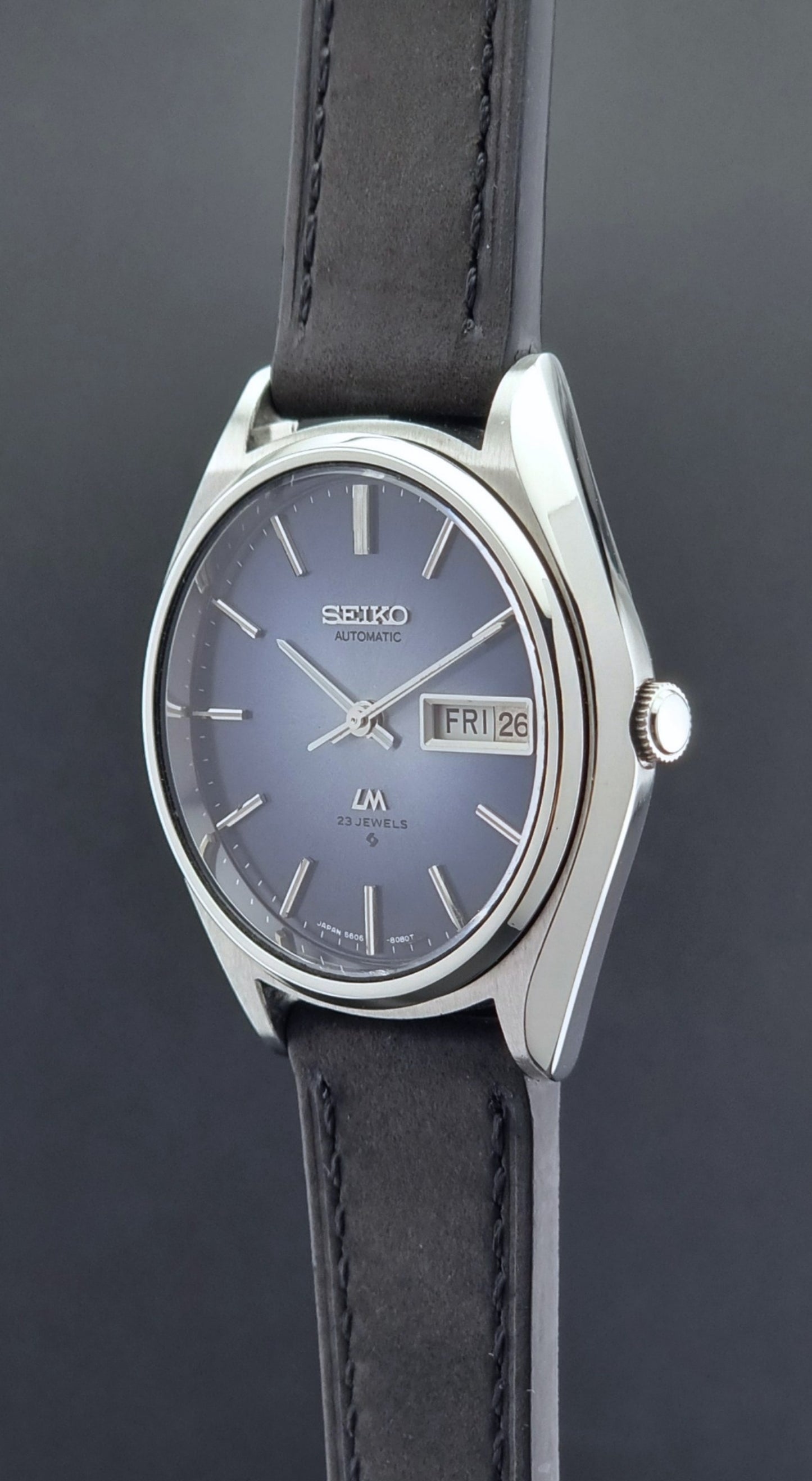 Vintage Seiko Wristwatch LordMatic 5606-8050 with blue gradient dial on a dark surface crown profile view
