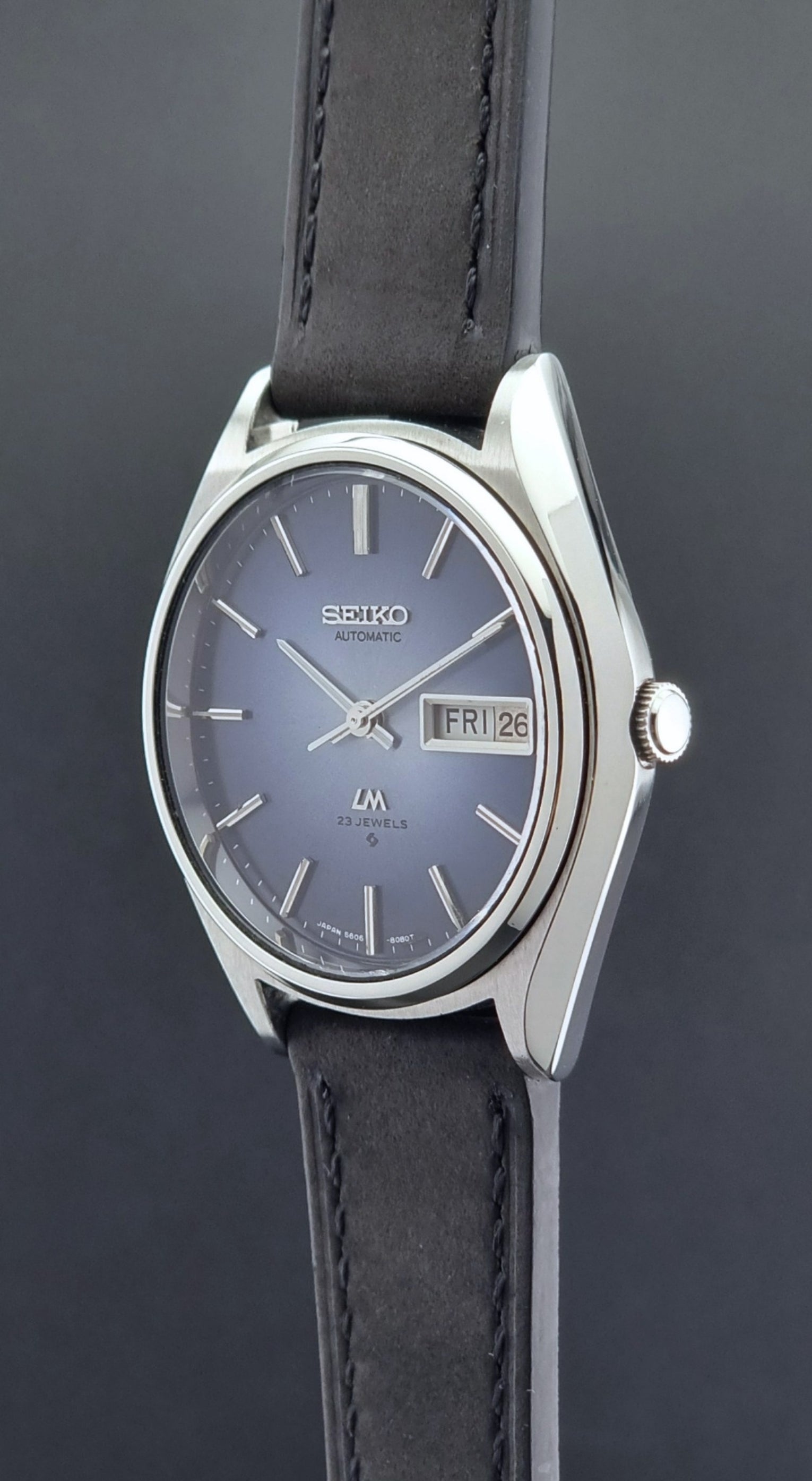 Vintage Seiko Wristwatch LordMatic 5606-8050 with blue gradient dial on a dark surface crown profile view