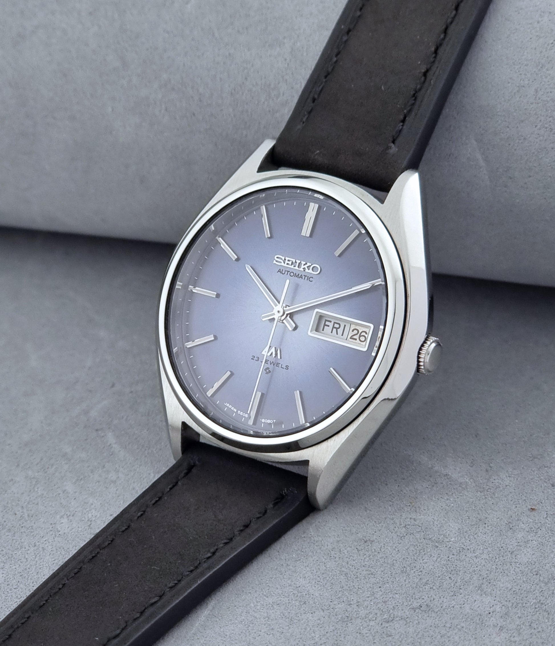 Vintage Seiko Wristwatch LordMatic 5606-8050 with blue gradient dial on a dark surface crown view