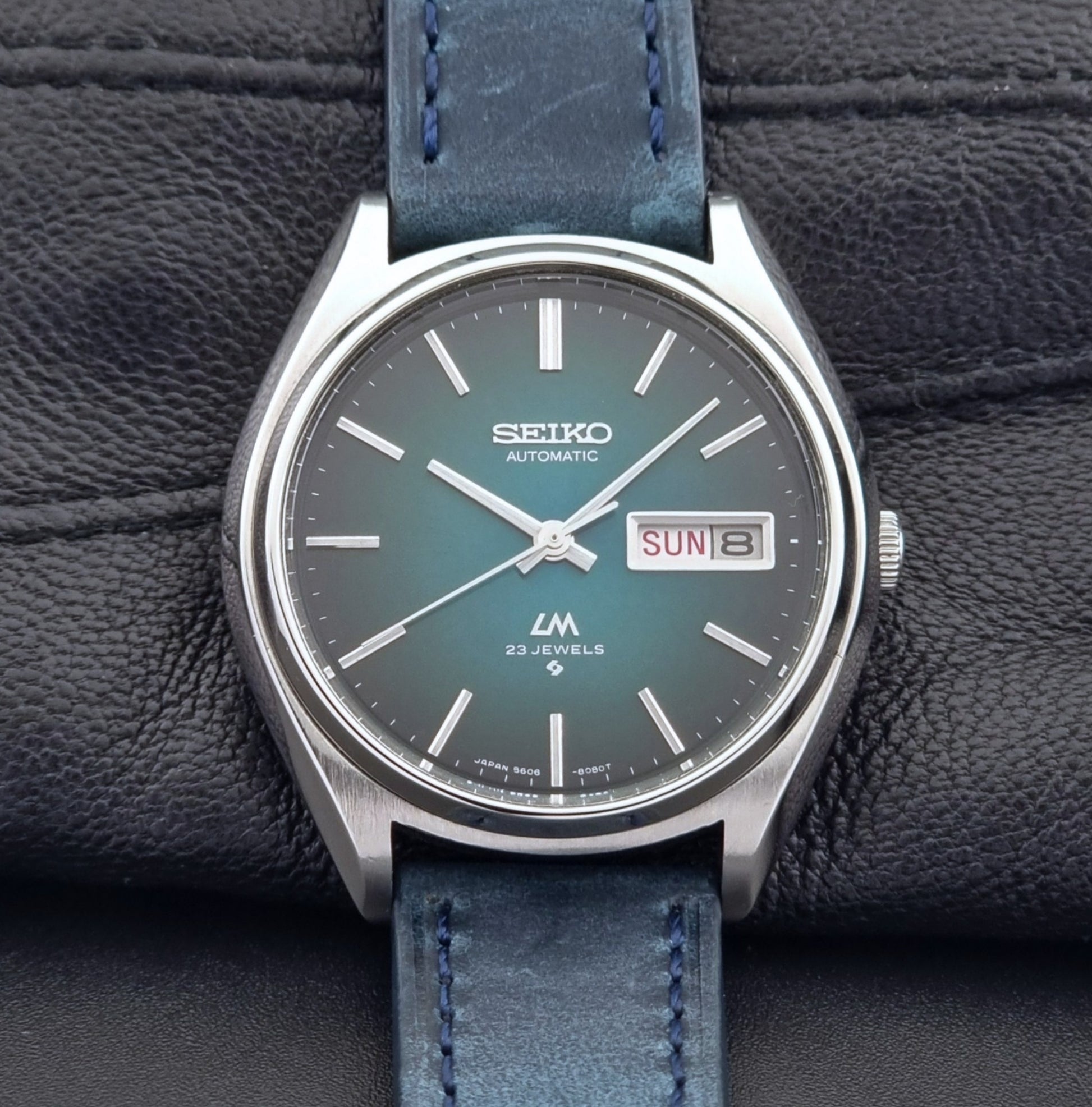 Vintage Seiko watch LordMatic 5606-8050 with blue leather strap on a dark gray background close up front view