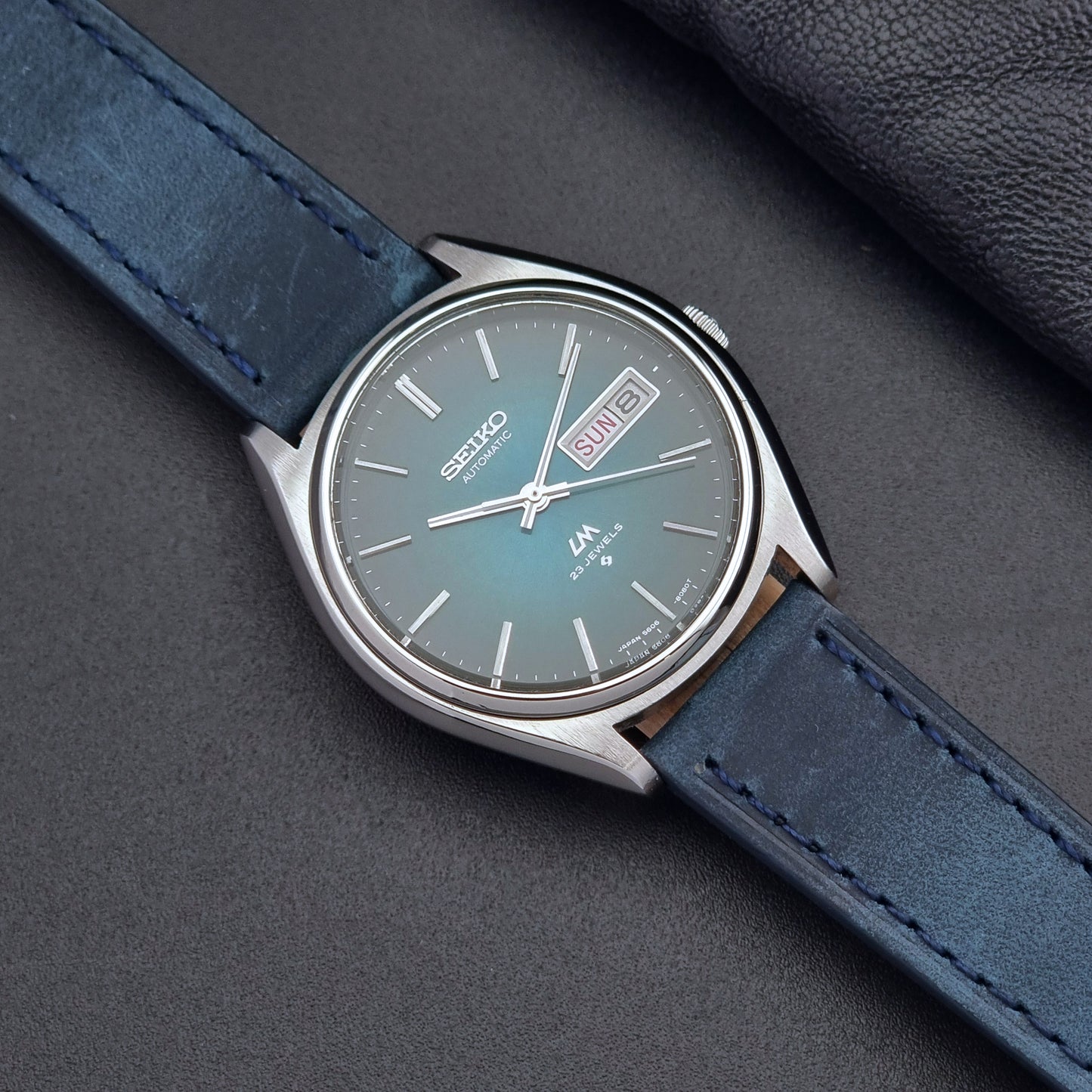 Vintage Seiko watch LordMatic 5606-8050 with blue leather strap on a dark gray background