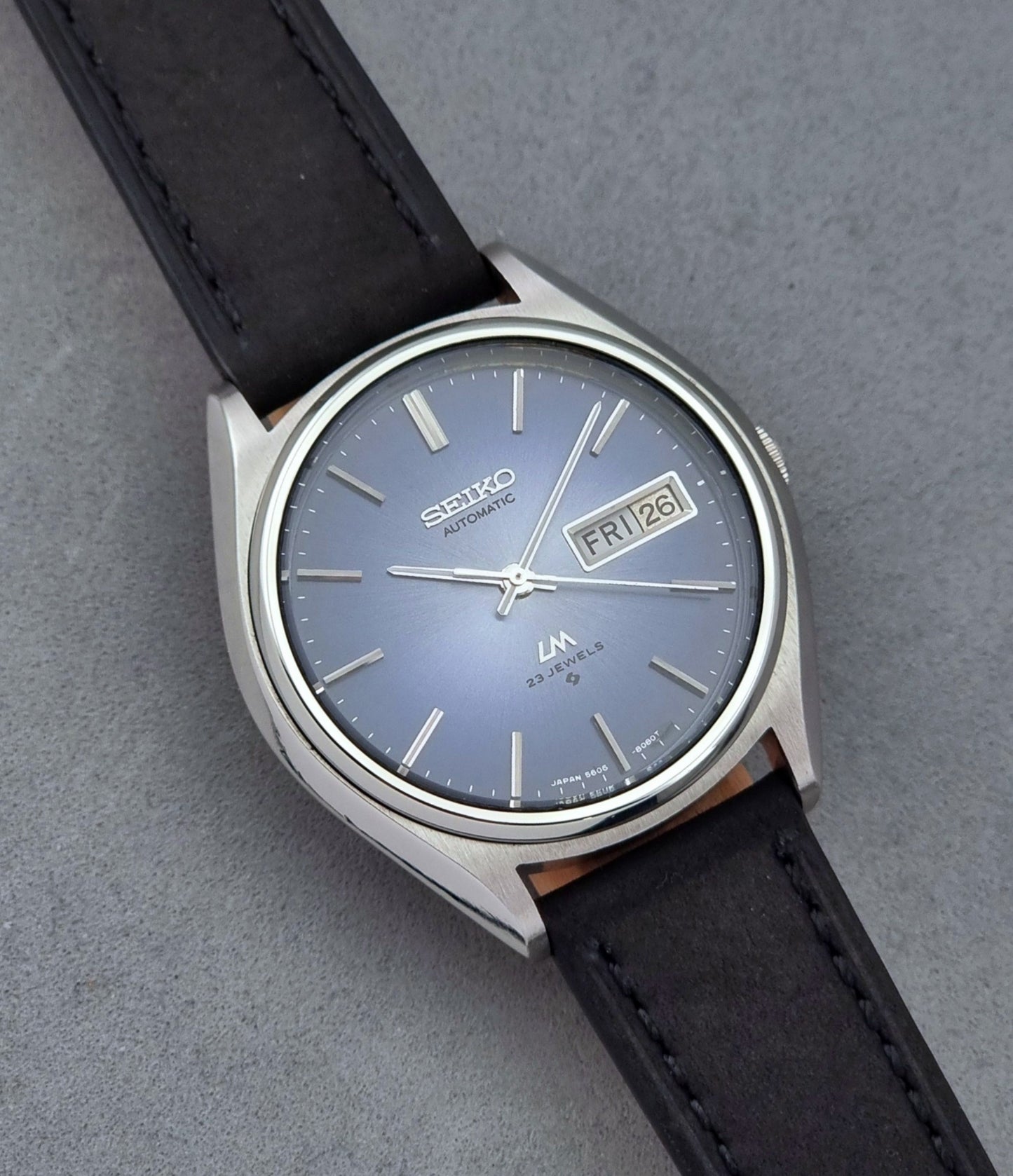 Vintage Seiko Wristwatch LordMatic 5606-8050 with blue gradient dial on a dark surface close dial view