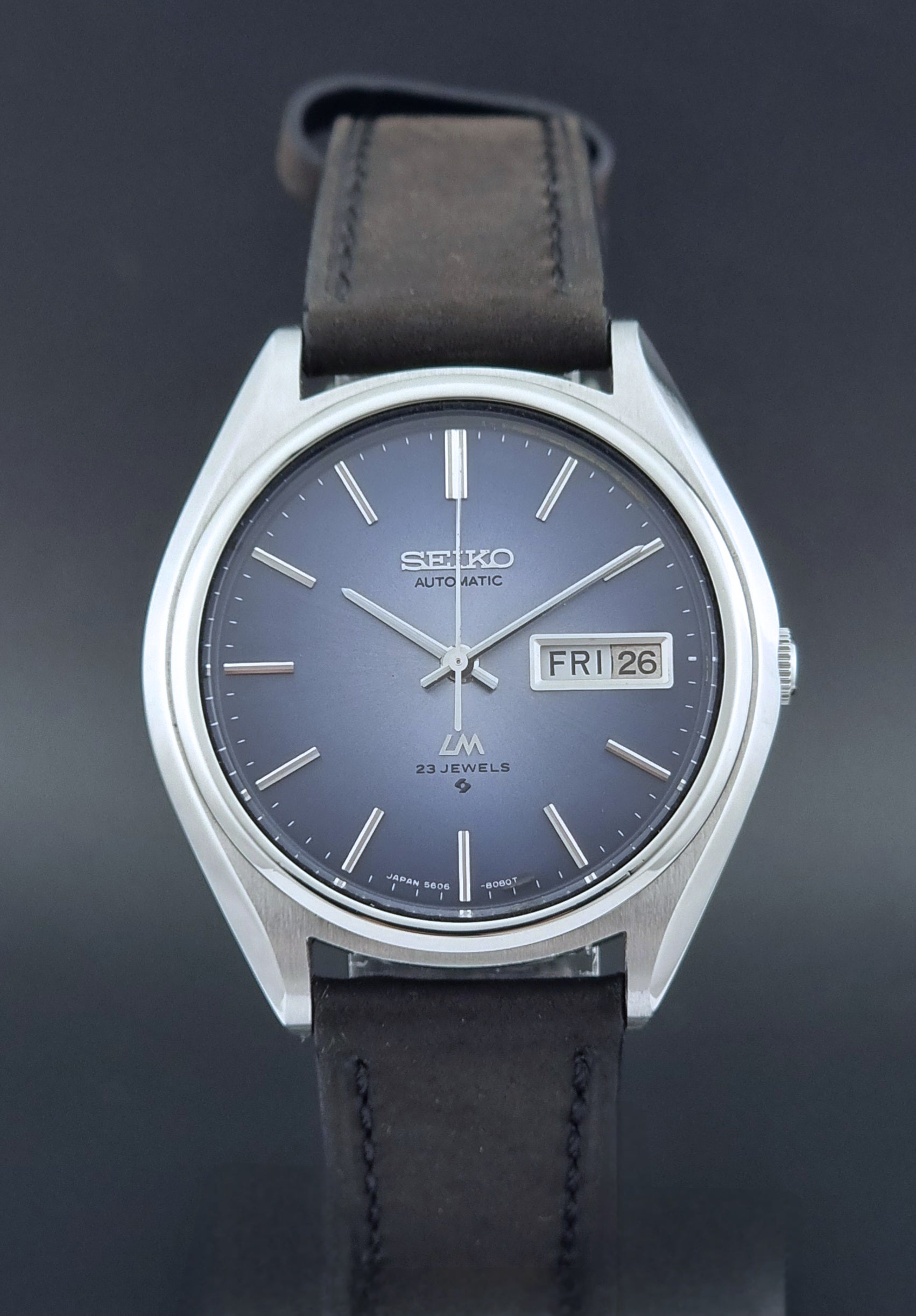 Vintage Seiko Wristwatch LordMatic 5606-8050 with blue gradient dial on a dark surface dial view