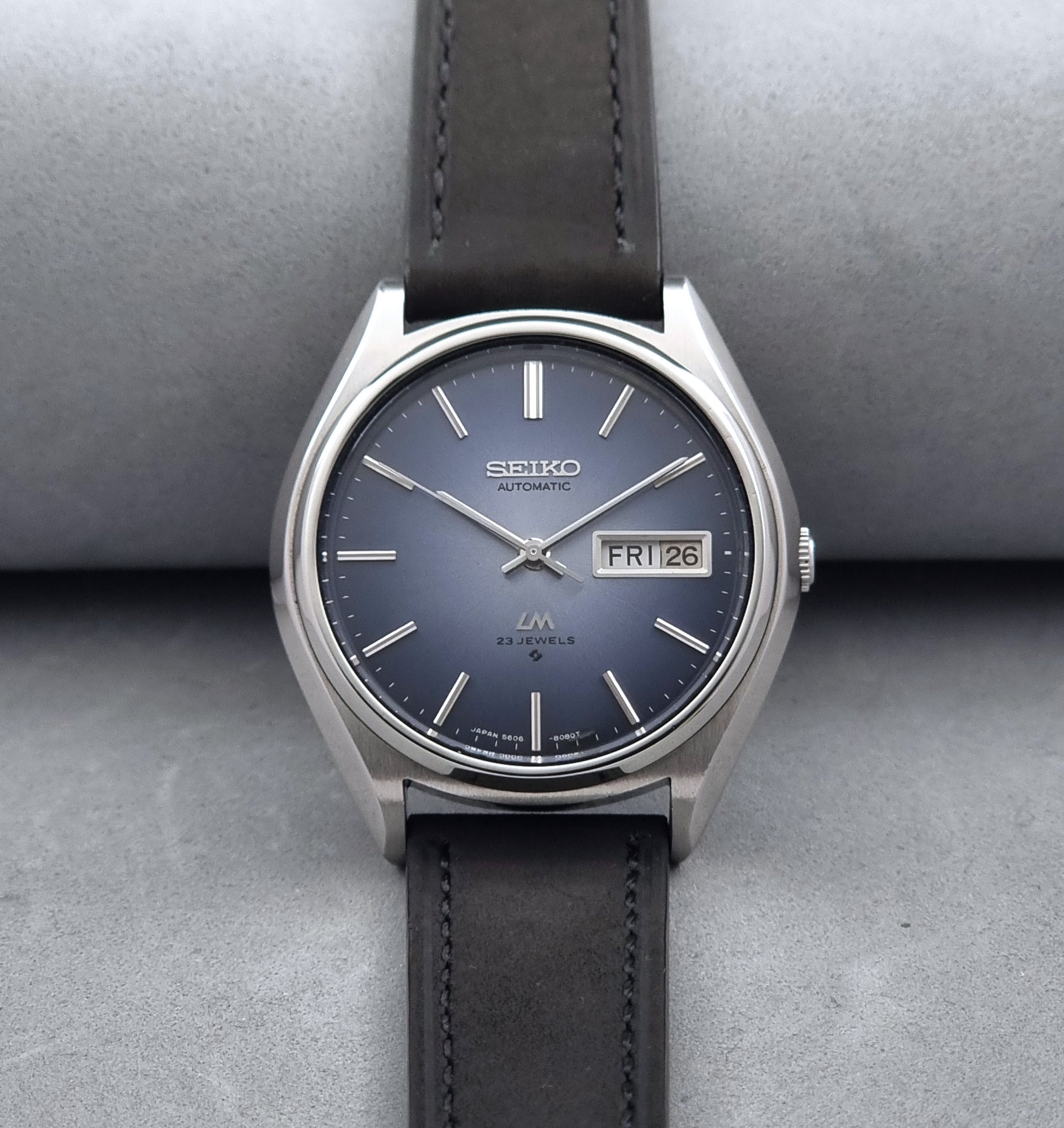 Vintage Seiko Wristwatch LordMatic 5606-8050 with blue gradient dial on a dark surface front view