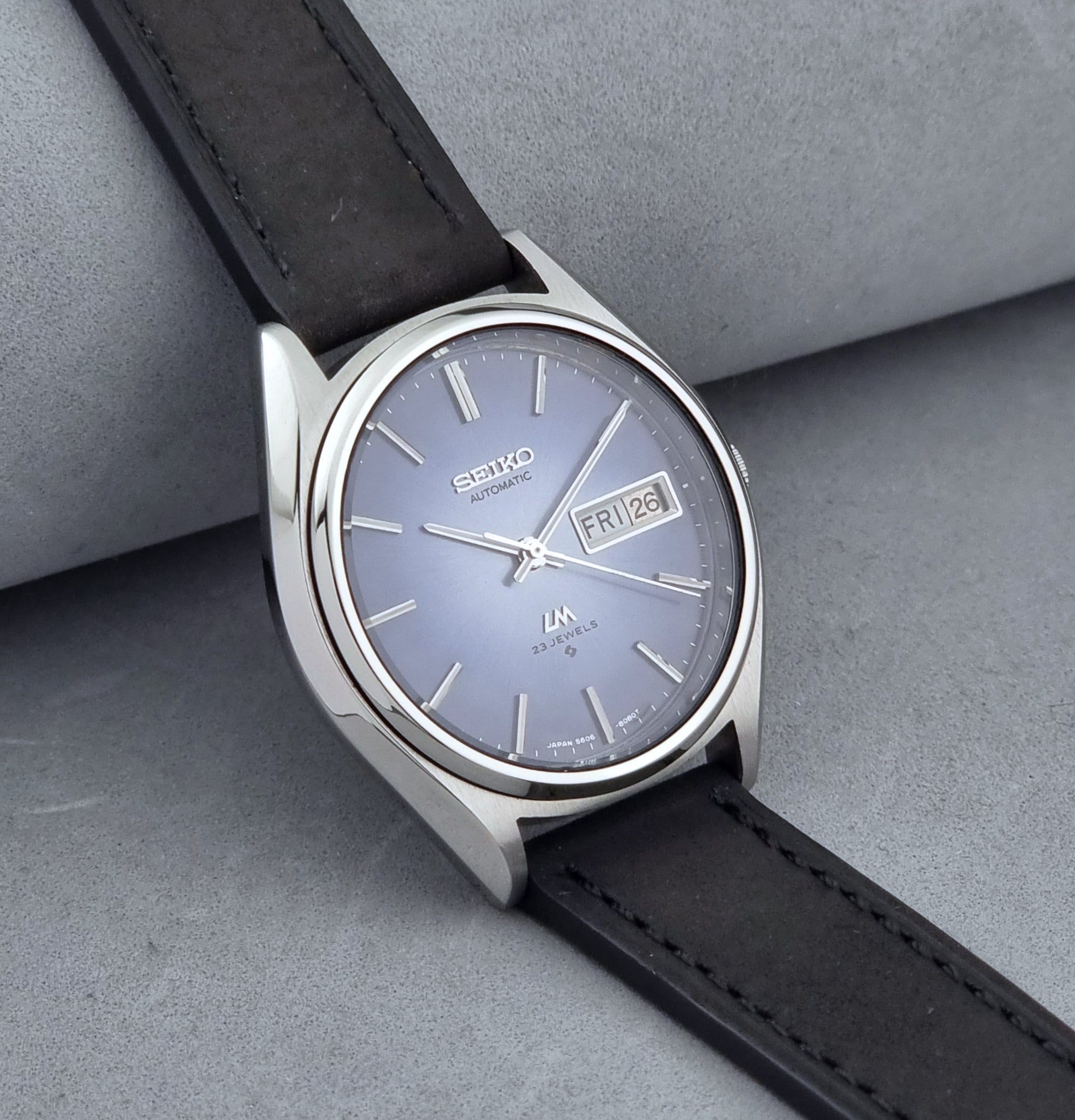 Vintage Seiko Wristwatch LordMatic 5606-8050 with blue gradient dial on a dark surface side view