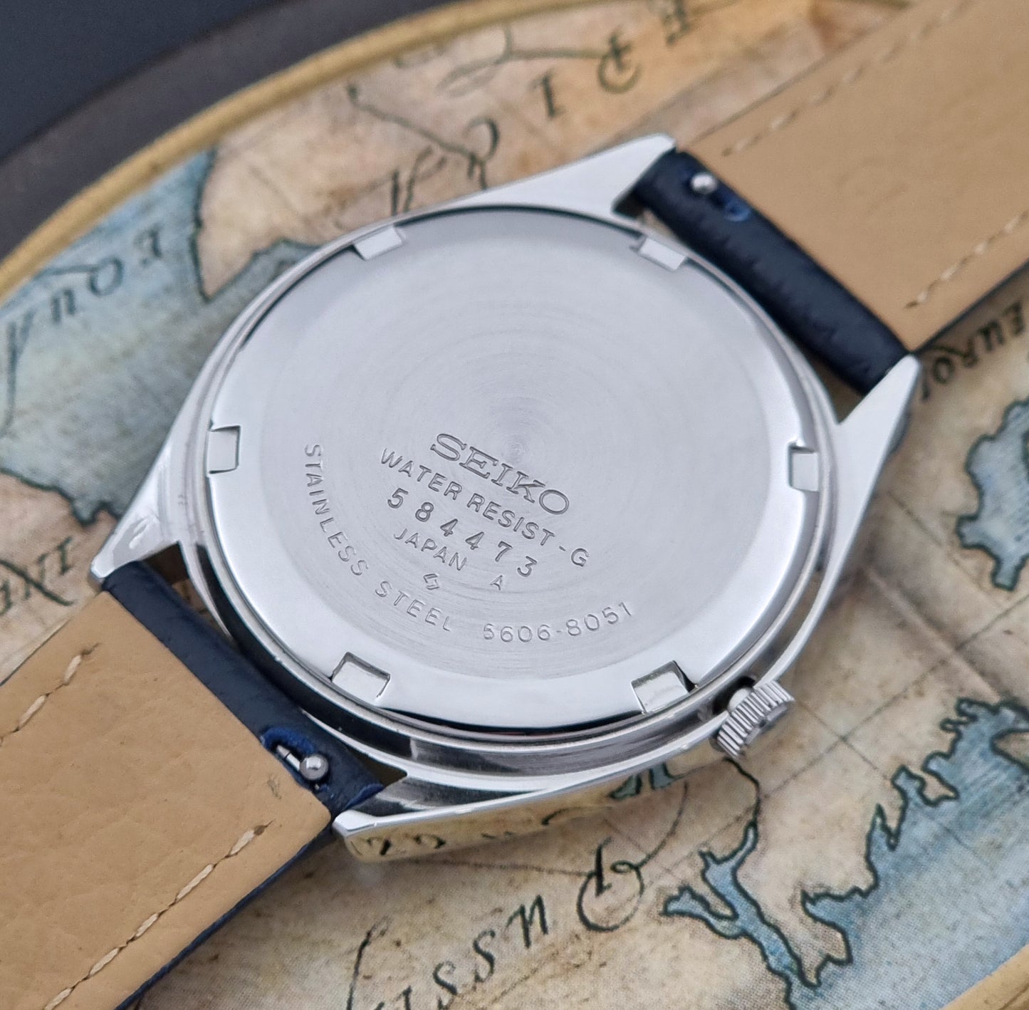 Vintage Seiko Wristwatch LordMatic 5606-8051 with blue strap with blue strap on a world map background case back