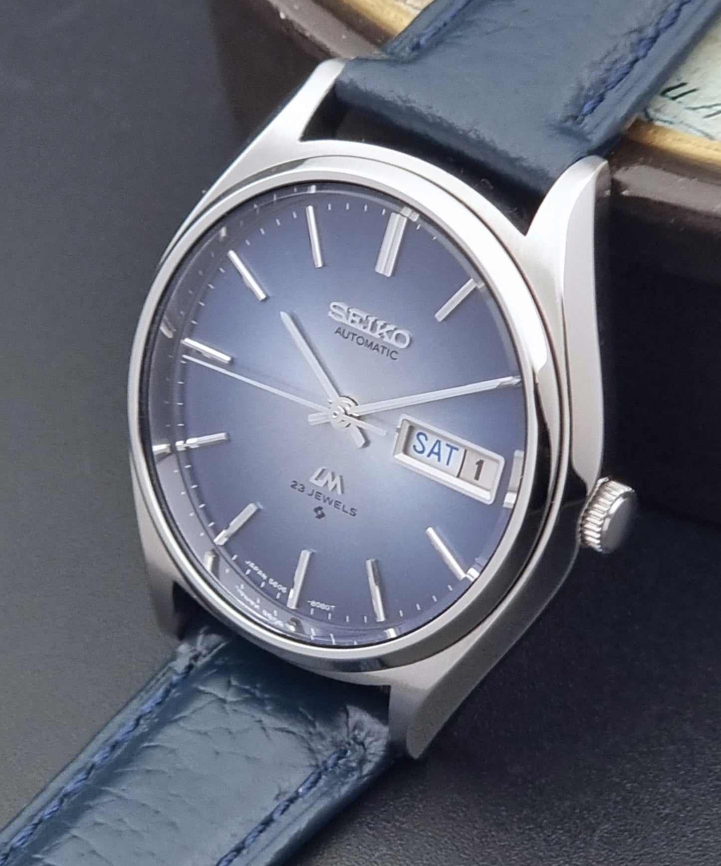 Vintage Seiko Wristwatch LordMatic 5606-8051 with blue strap with blue strap on a dark background crown side