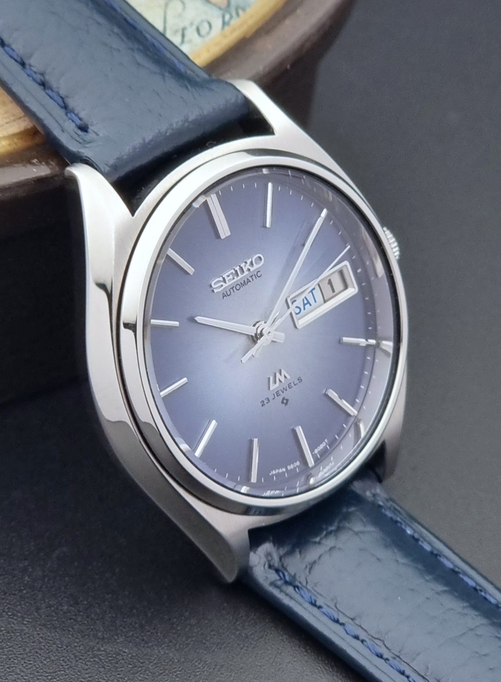 Vintage Seiko Wristwatch LordMatic 5606-8051 with blue strap with blue strap on a dark background side