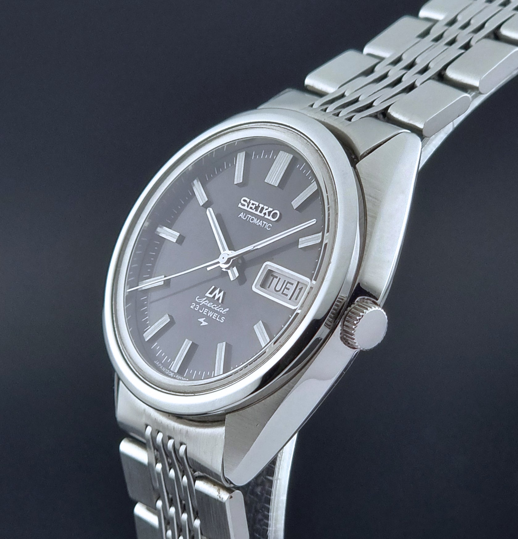 Vintage Seiko LordMatic Special 5206-6021 wristwatch with a dark gray face on a black background crown profile view