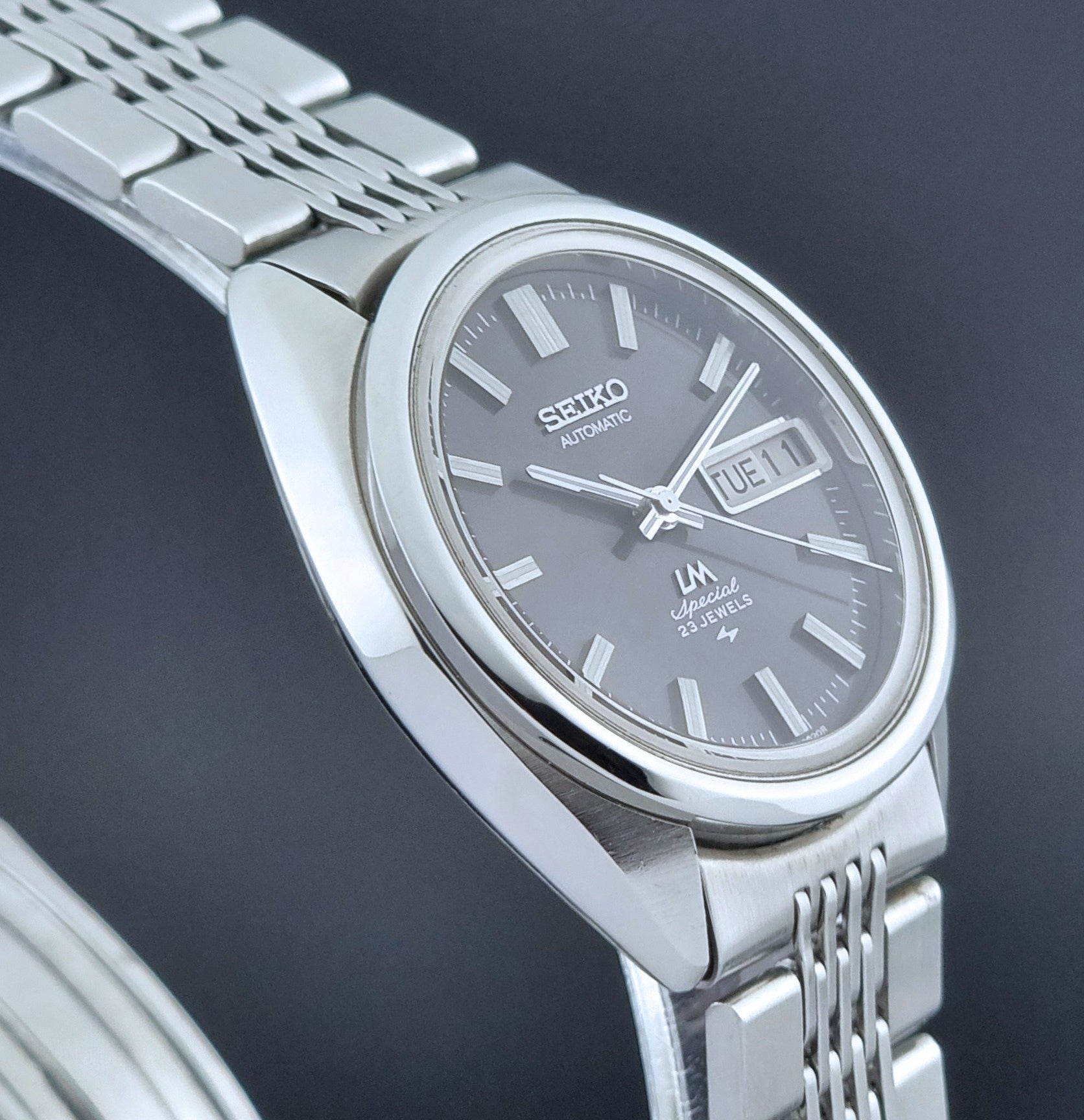 Vintage Seiko LordMatic Special 5206-6021 wristwatch with a dark gray face on a black background side profile view