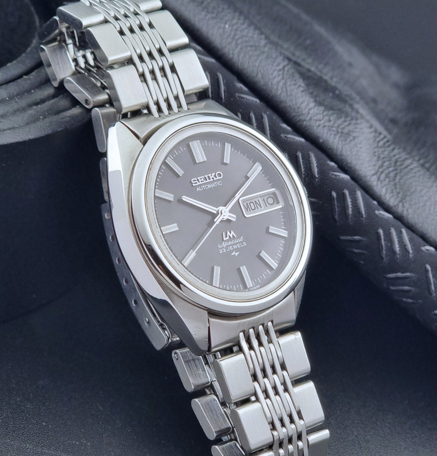 Vintage Seiko LordMatic Special 5206-6021 wristwatch with a dark gray face on a black background side view