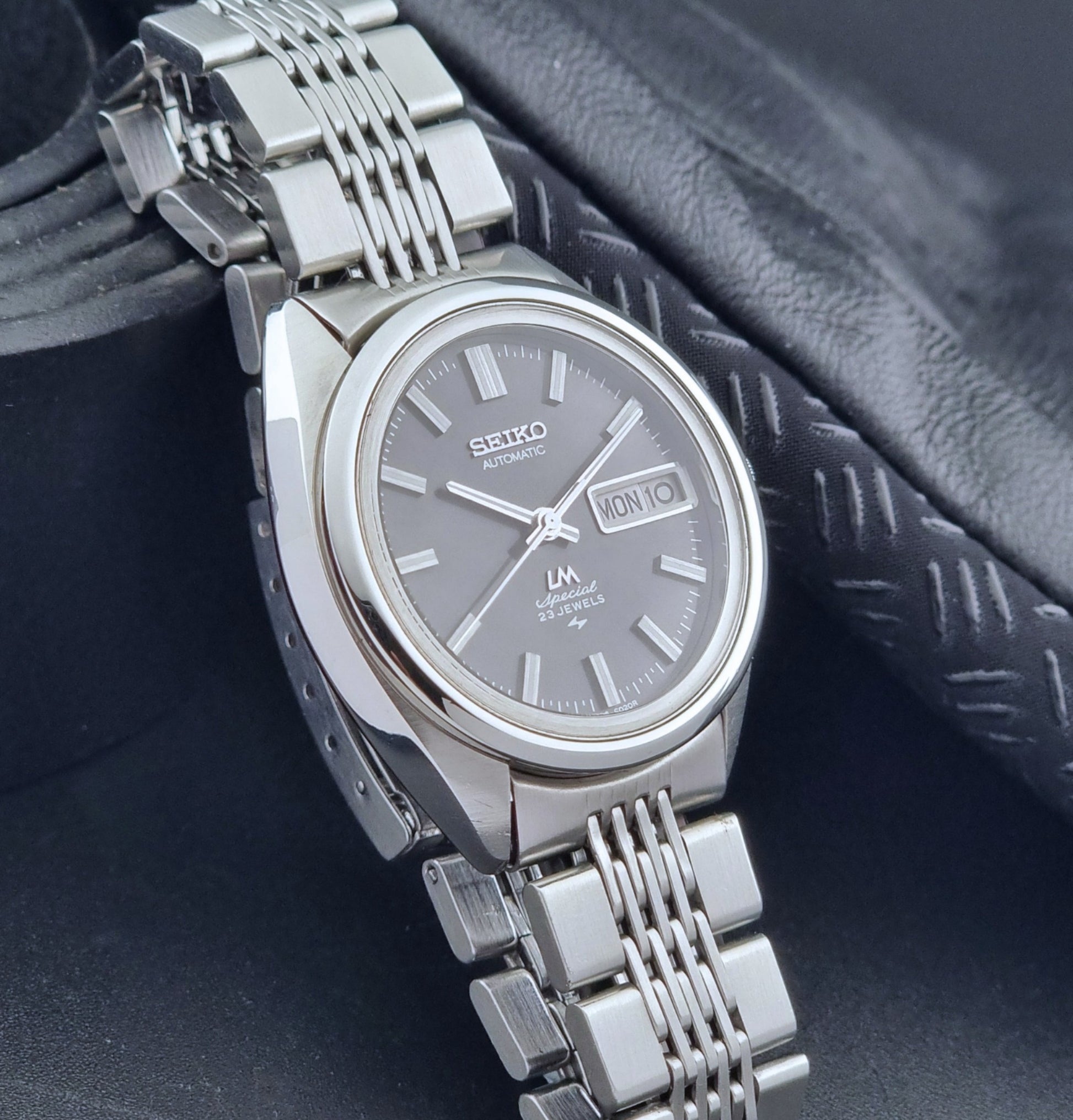 Vintage Seiko LordMatic Special 5206-6021 wristwatch with a dark gray face on a black background side view