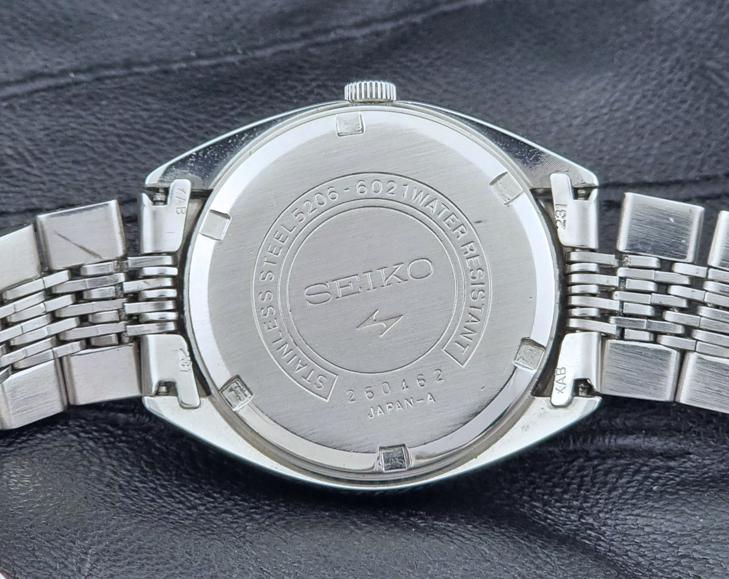 Vintage Seiko LordMatic Special 5206-6021 wristwatch with a dark gray face on a black background case back view