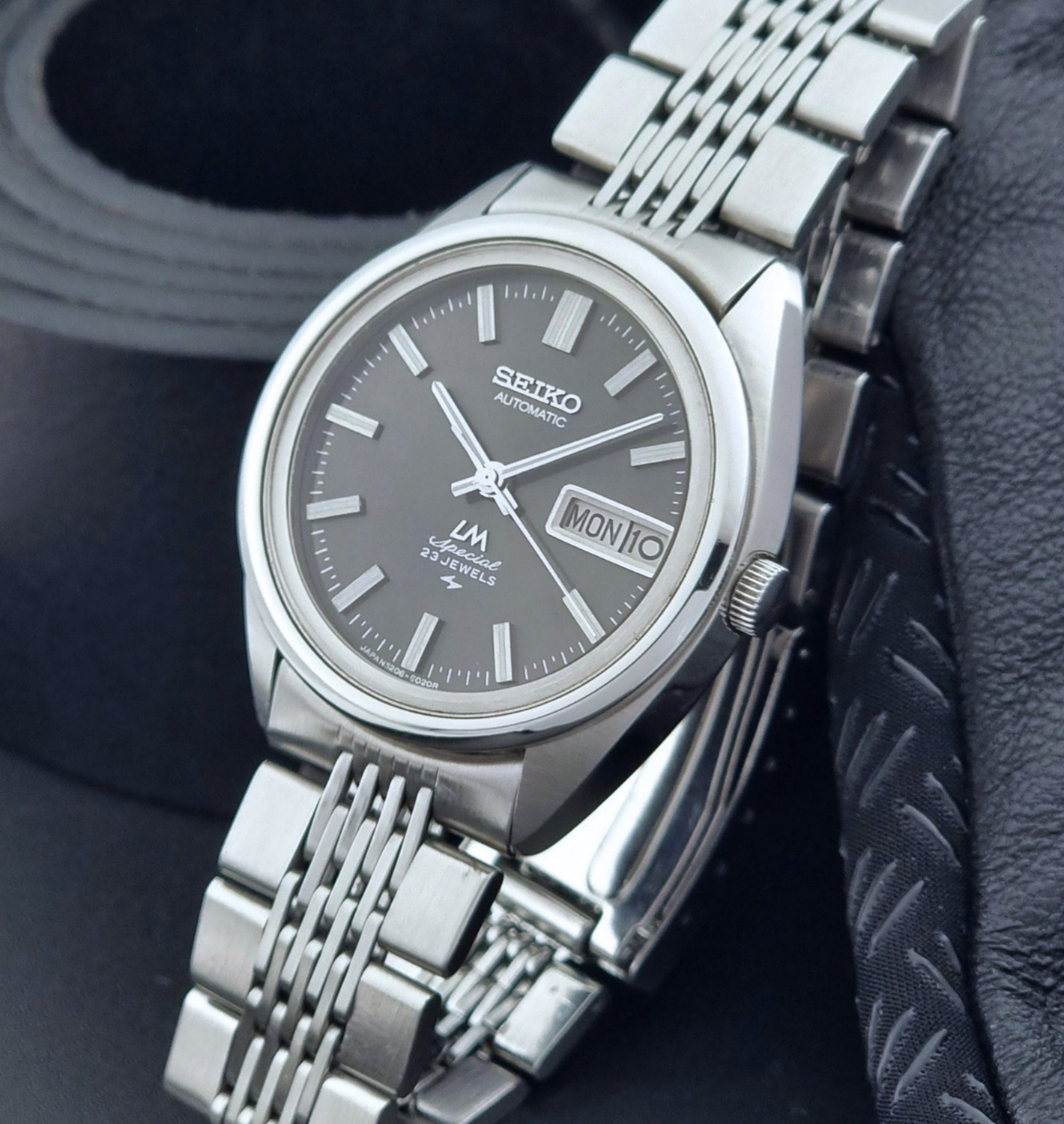 Vintage Seiko LordMatic Special 5206-6021 wristwatch with a dark gray face on a black background crown